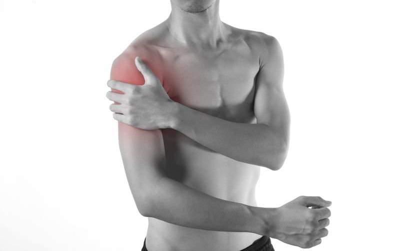 Man clutching his shoulder, with a red highlight indicating pain.