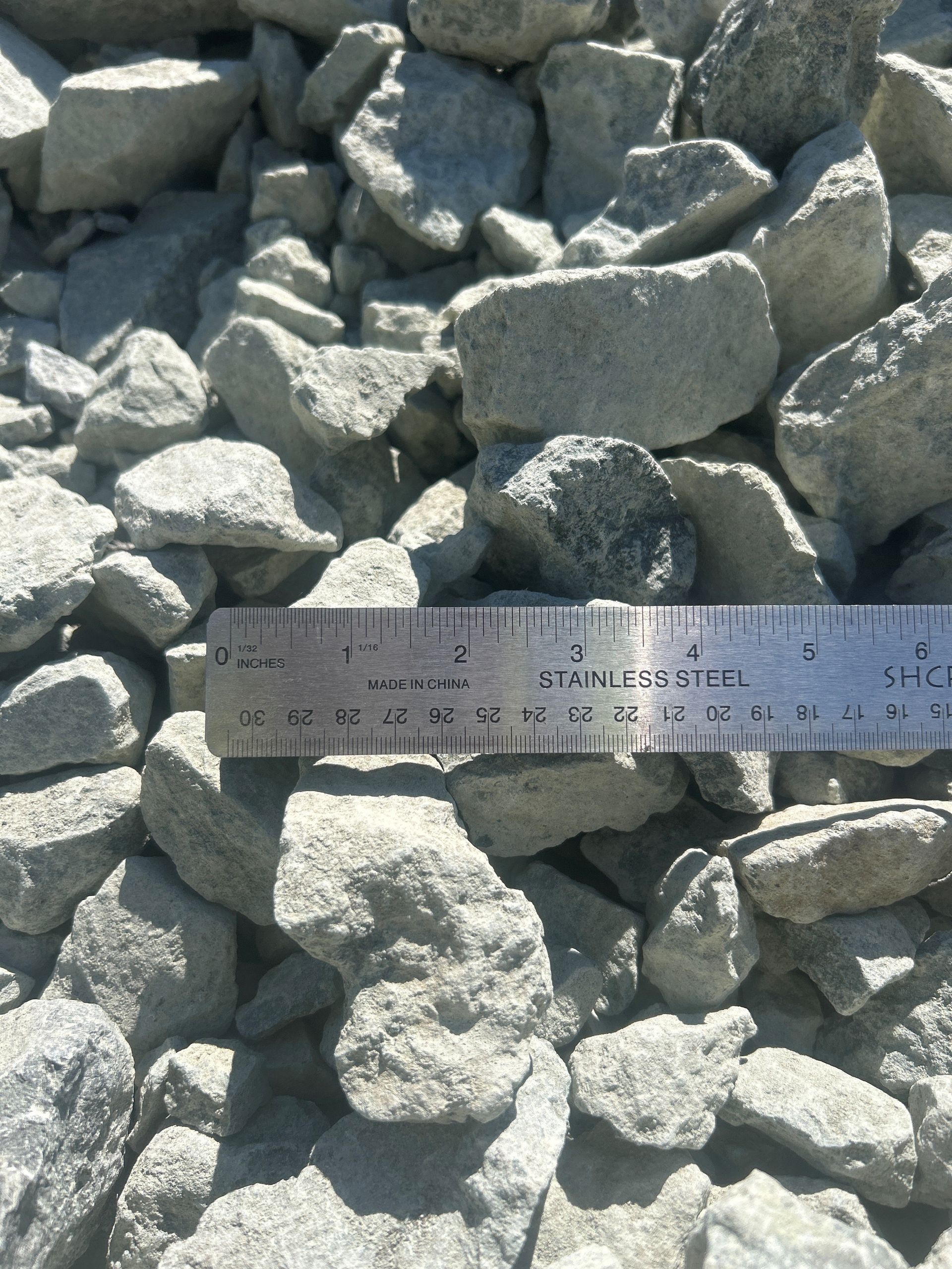 Gray rocks with a metal ruler placed among them.