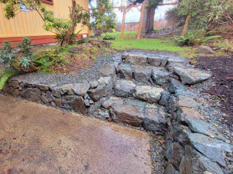 Stone steps and retaining wall leading to a grassy yard.