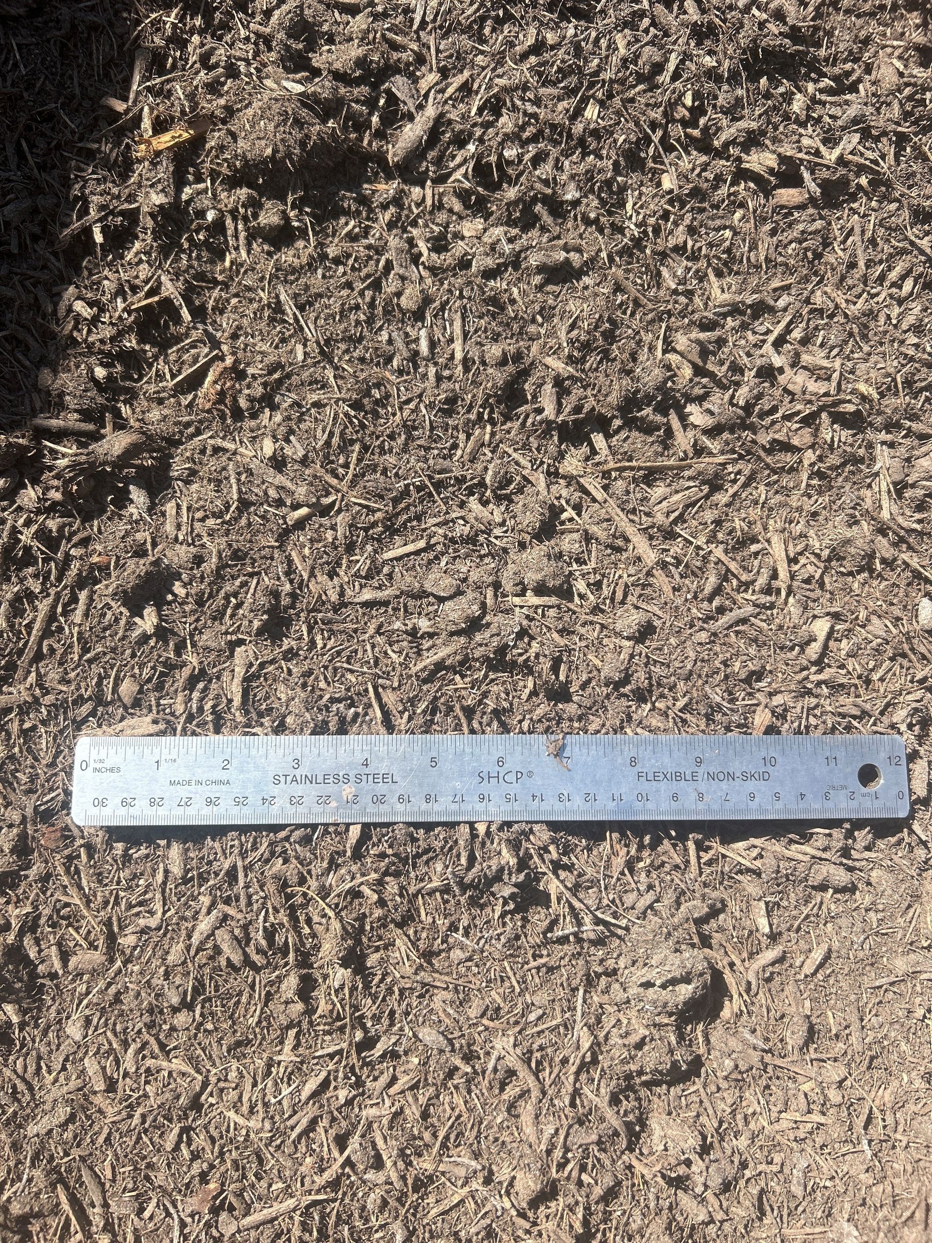 Brown soil with a metal ruler placed horizontally.
