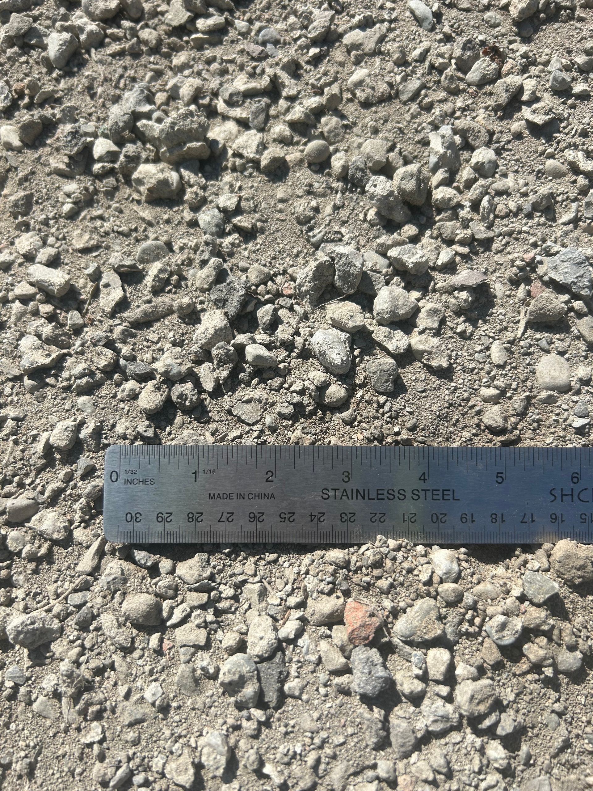 Gravel aggregate with a ruler for scale. The gravel is light gray.