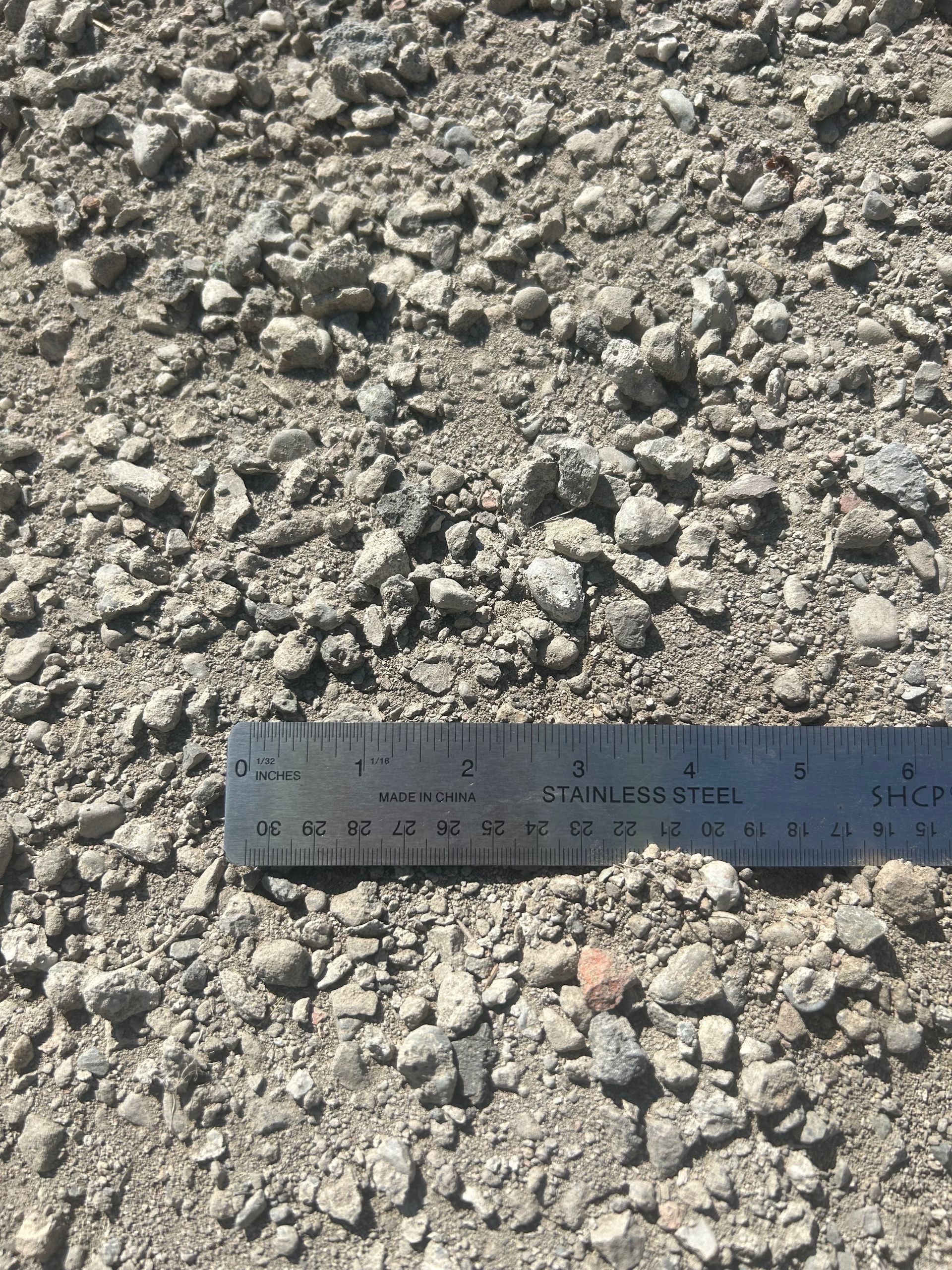 Crushed stone aggregate with a metal ruler for scale.
