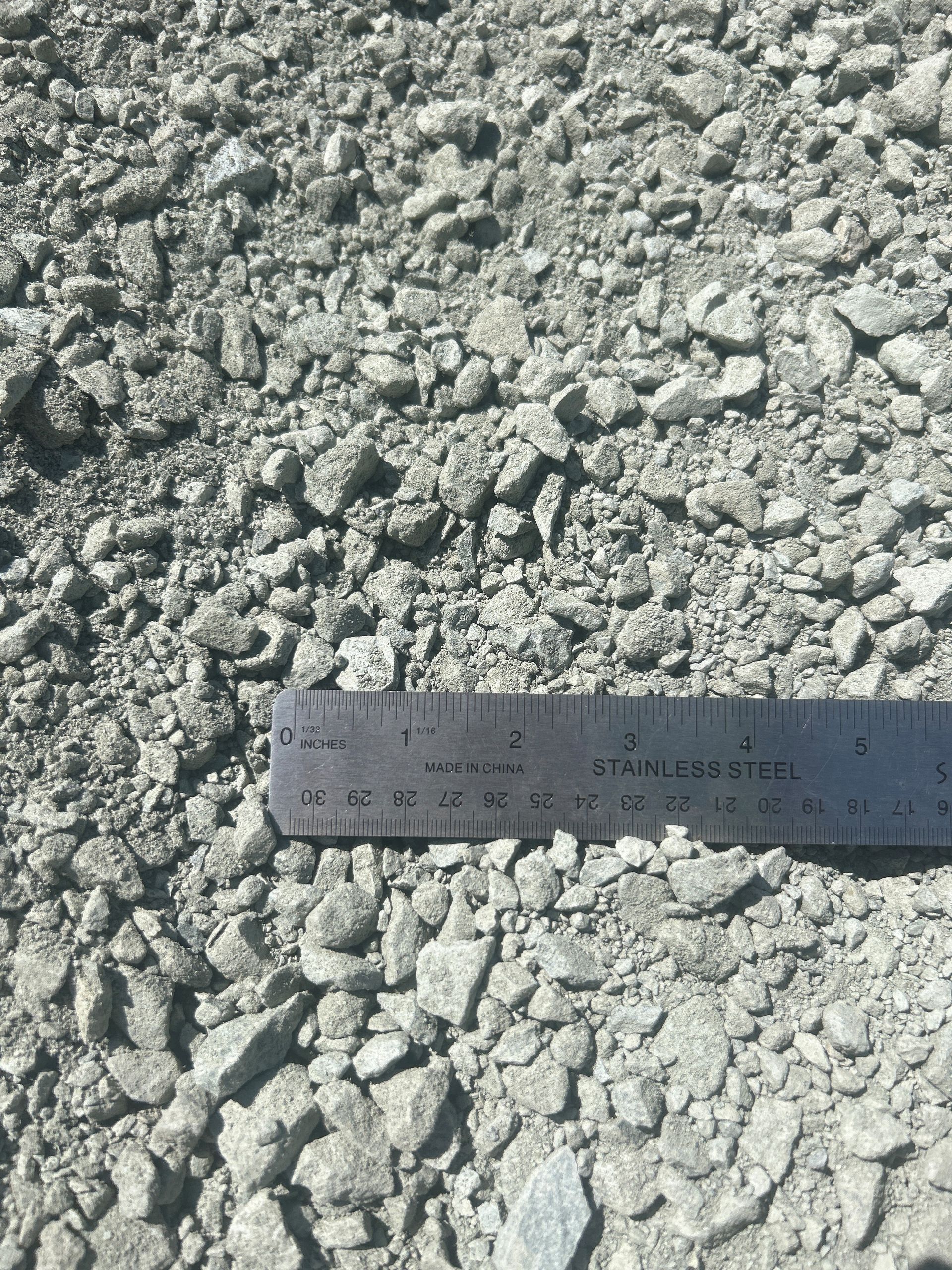 Crushed aggregate with a ruler for scale; gray rocks of varying sizes.