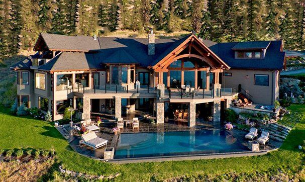 An aerial view of a large house with a swimming pool surrounded by trees.