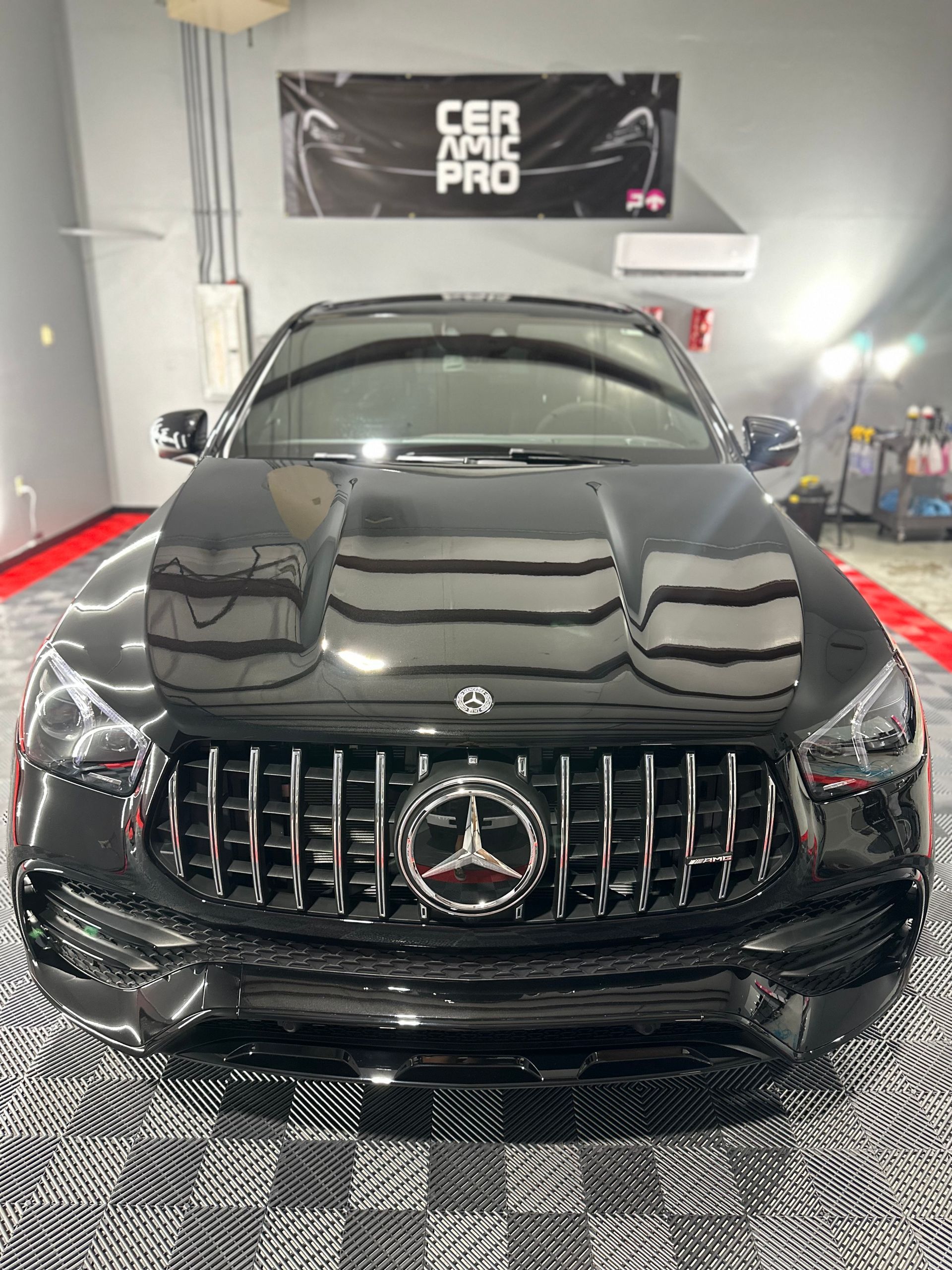 A black mercedes benz is parked in a garage.