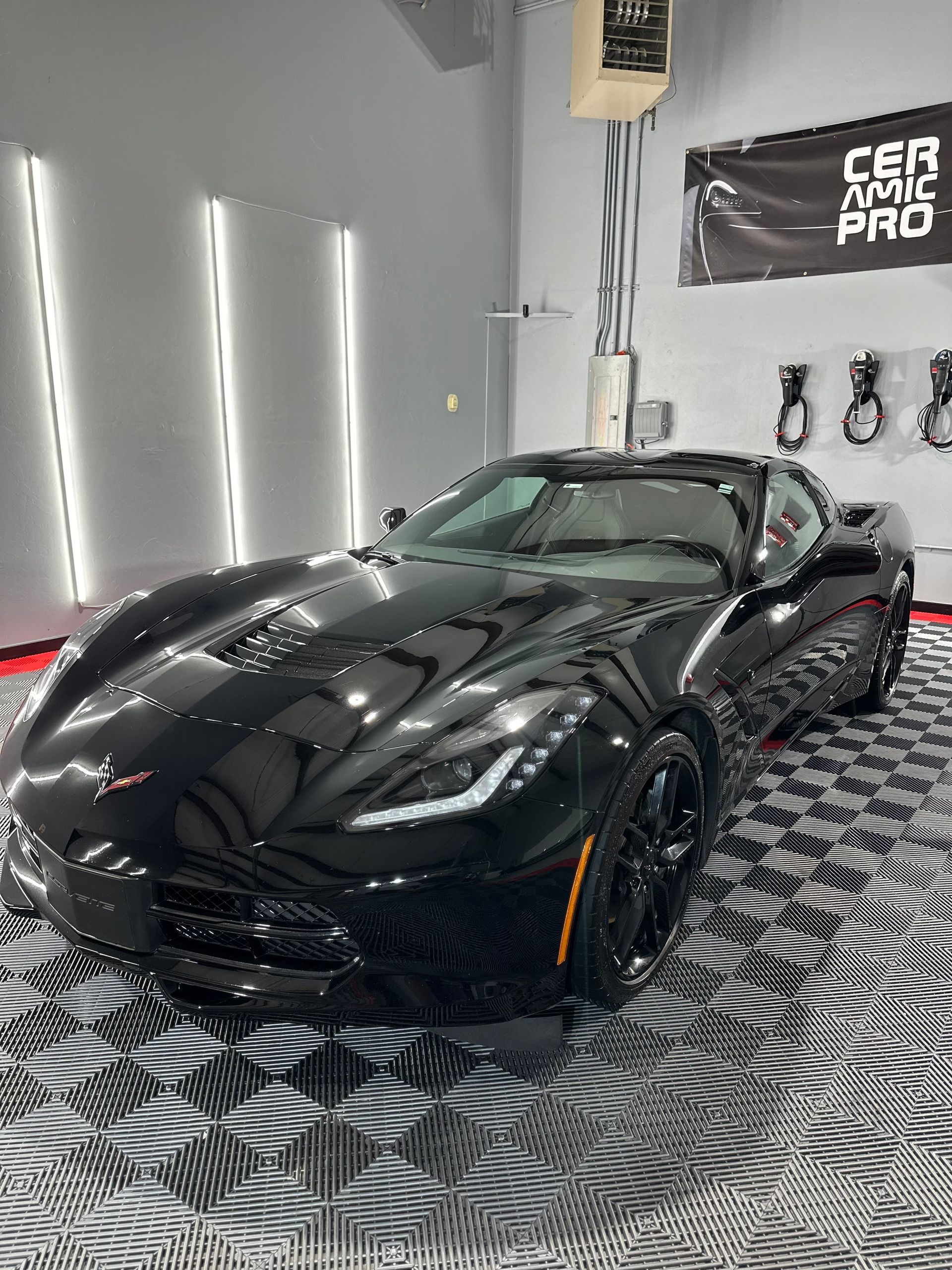 A black corvette is parked in a garage.