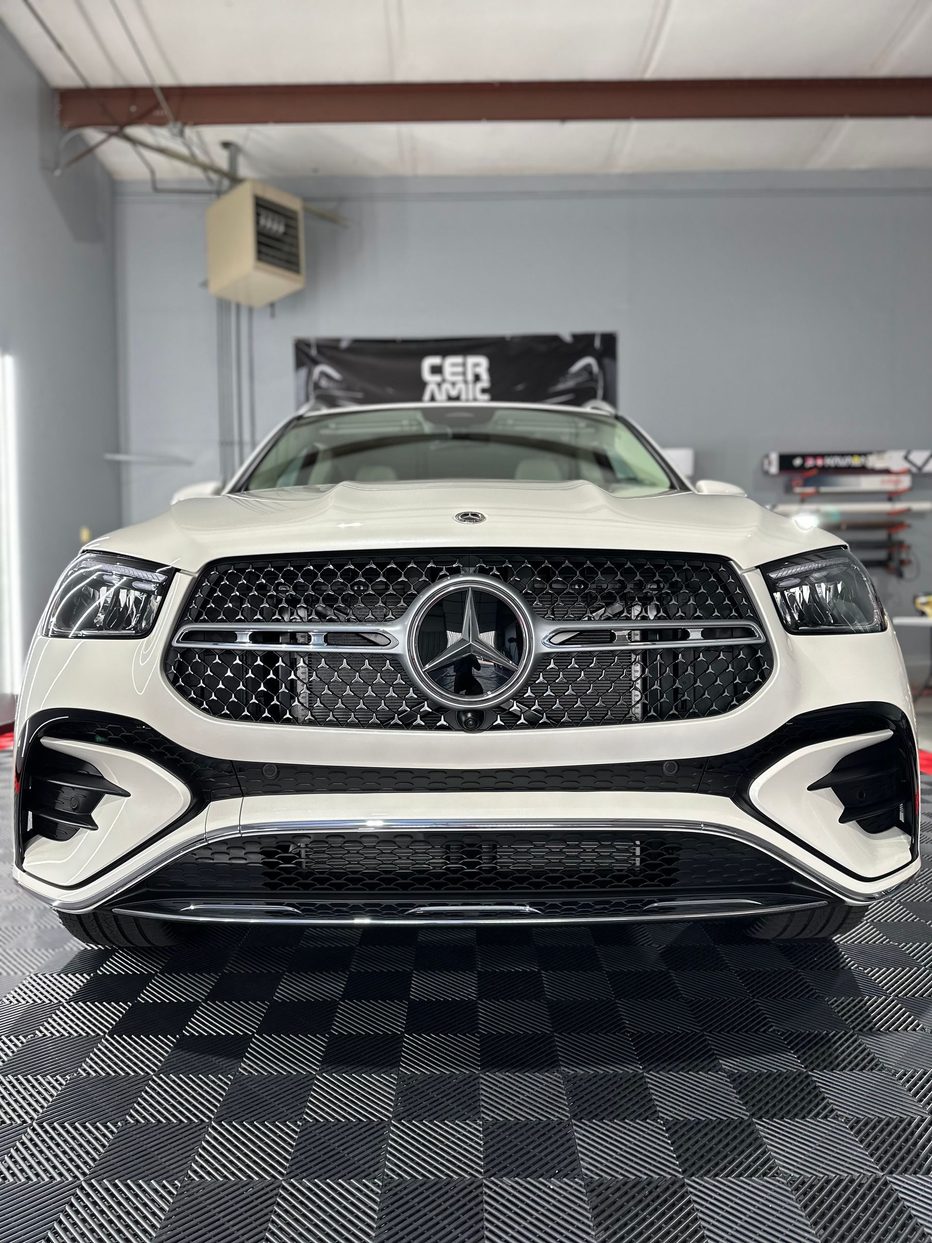 A white mercedes benz is parked in a garage.