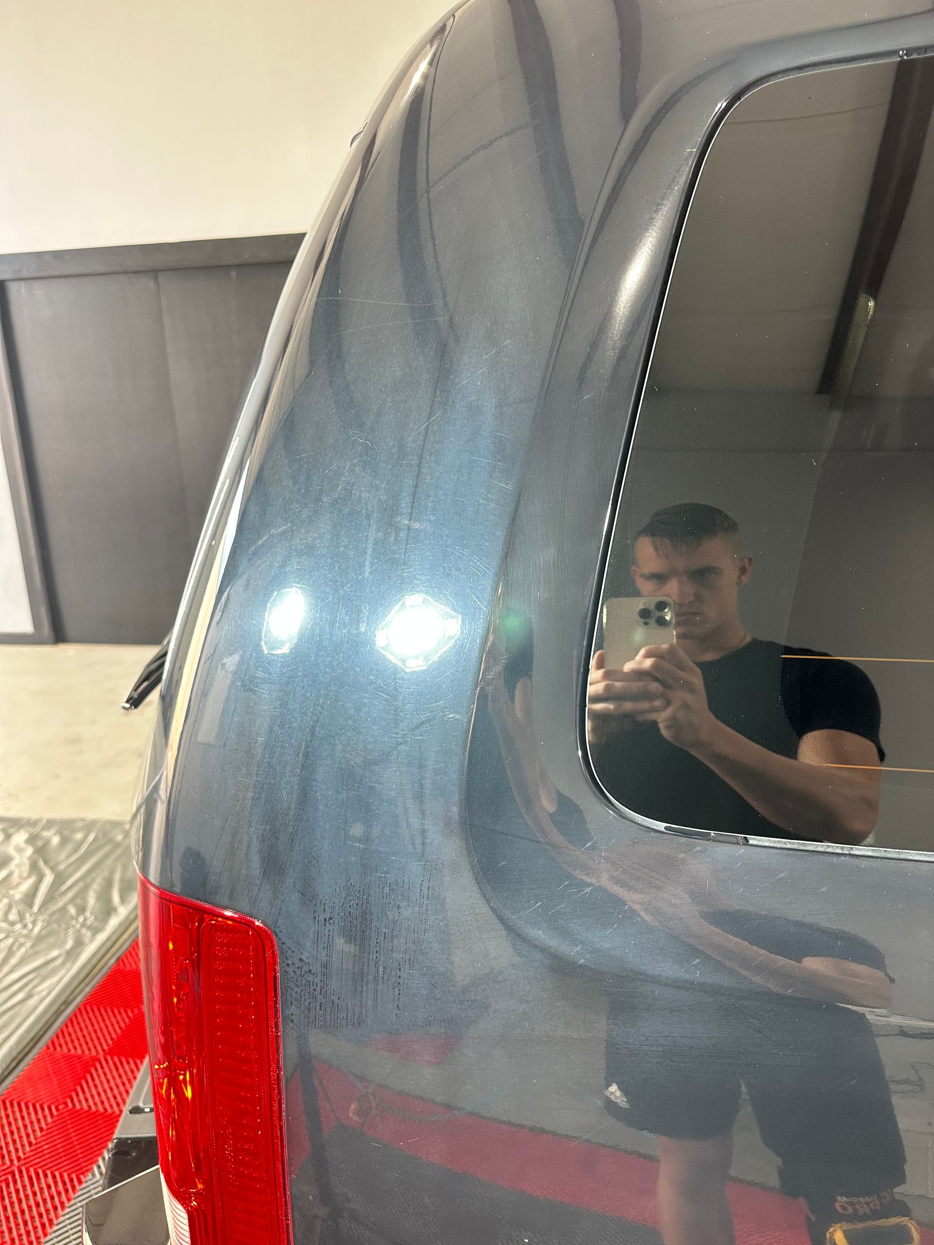 A man is taking a picture of himself in the window of a car.