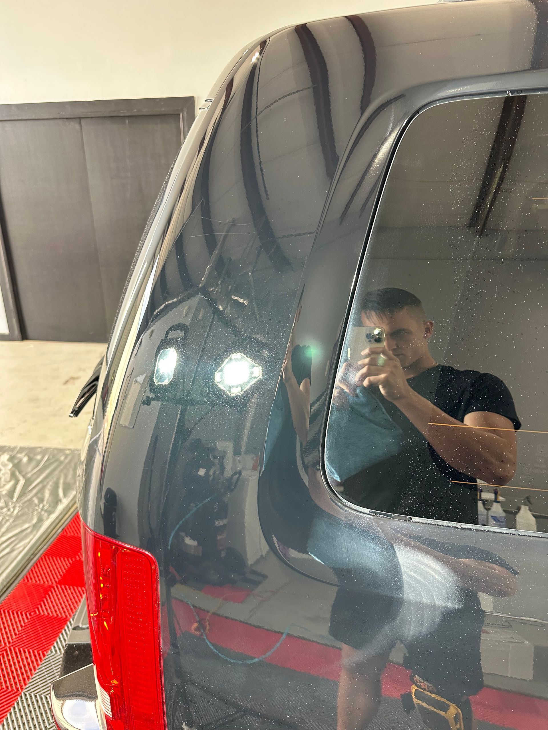 A man is taking a picture of himself in the window of a car.