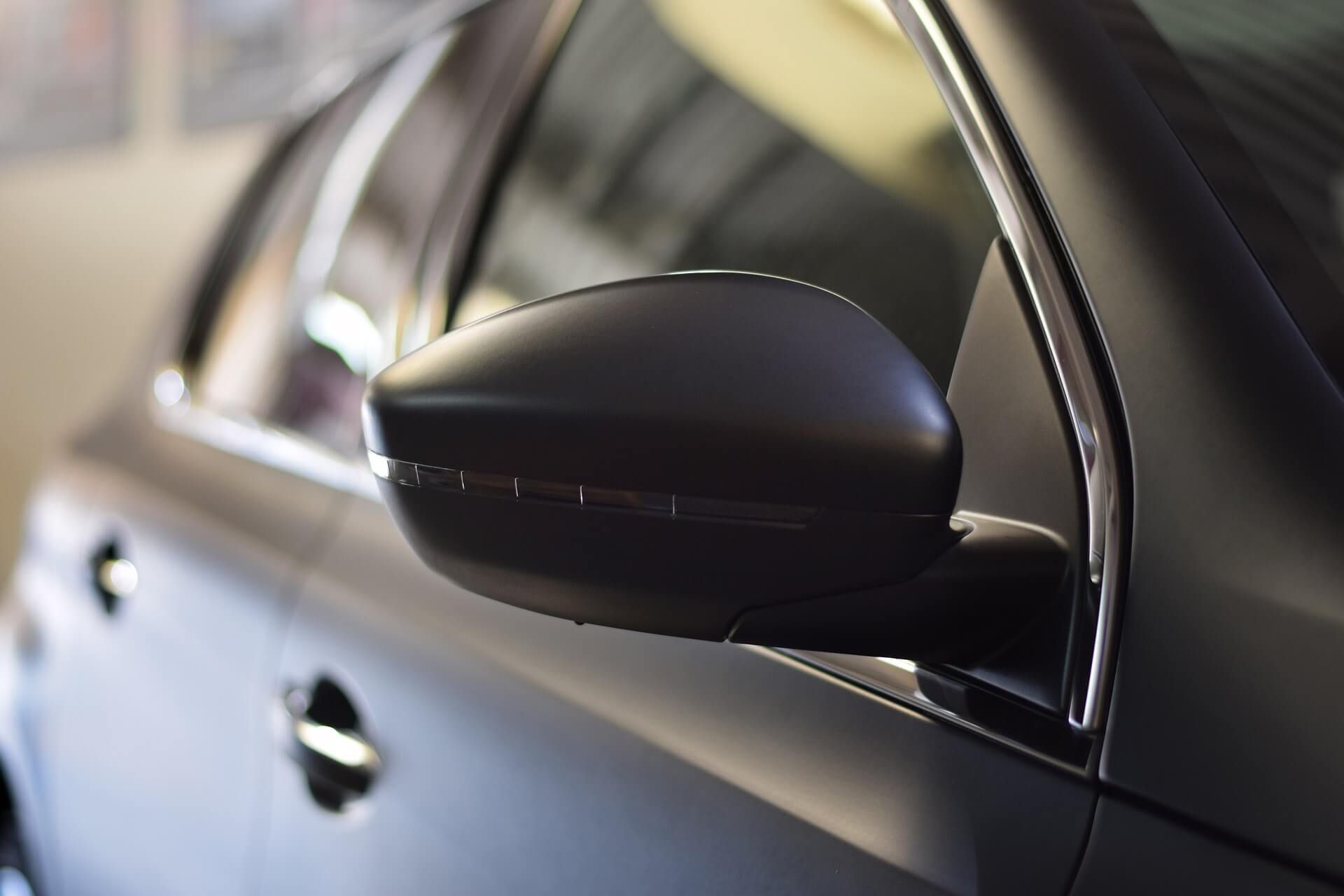 A close up of a black car 's side mirror