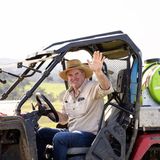 A man in a straw hat is sitting in a vehicle and waving