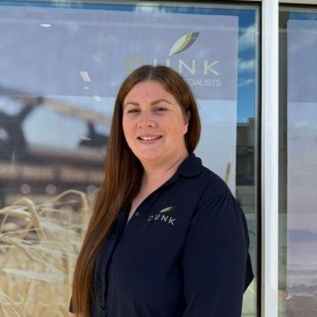 Woman standing outside a storefront in a navy shirt, smiling at the camera