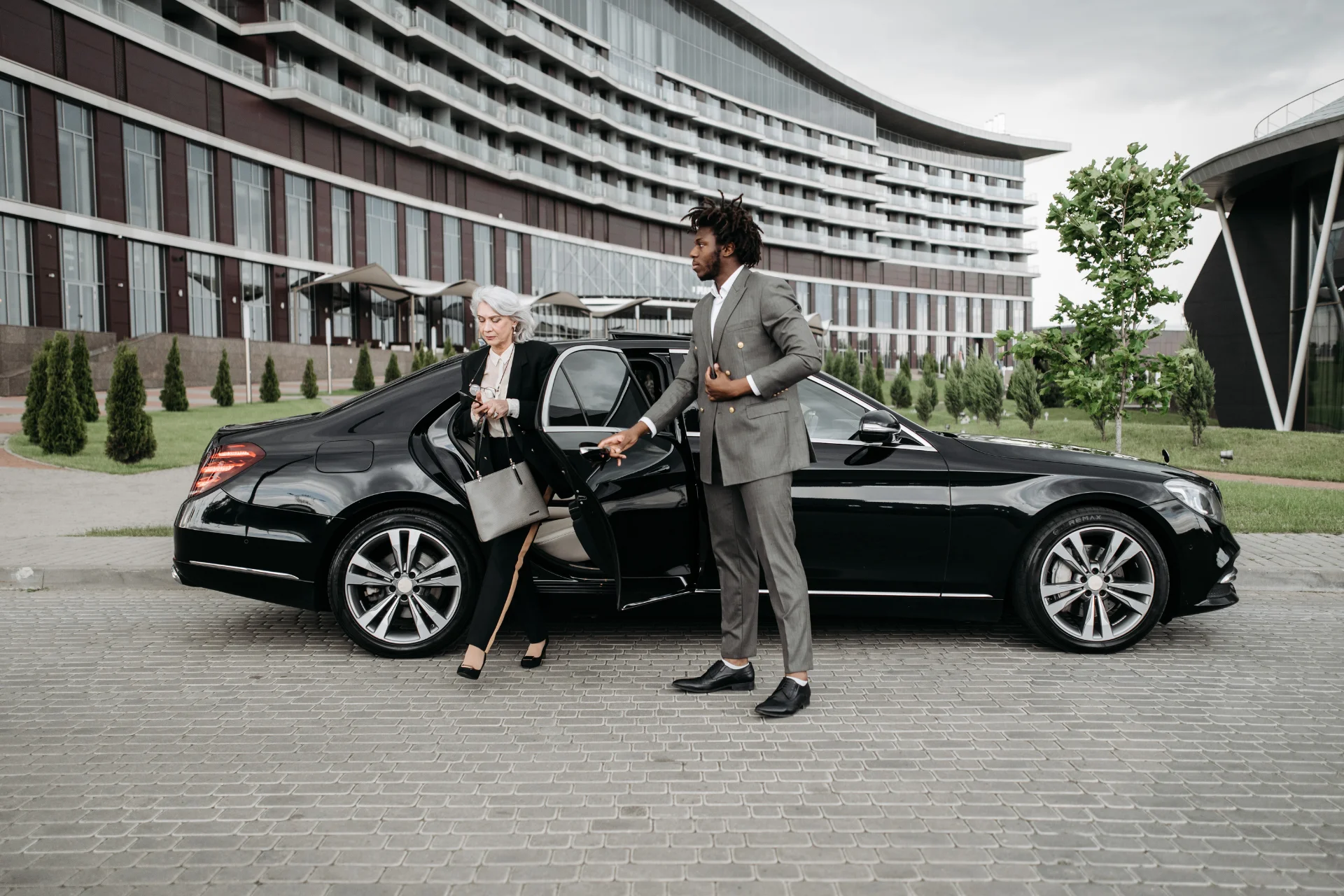 A man in a suit is helping a woman get out of a car.