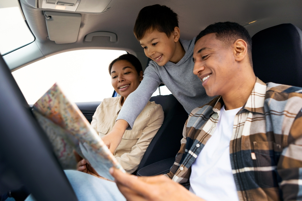 A family is sitting in the back seat of a car looking at a map.