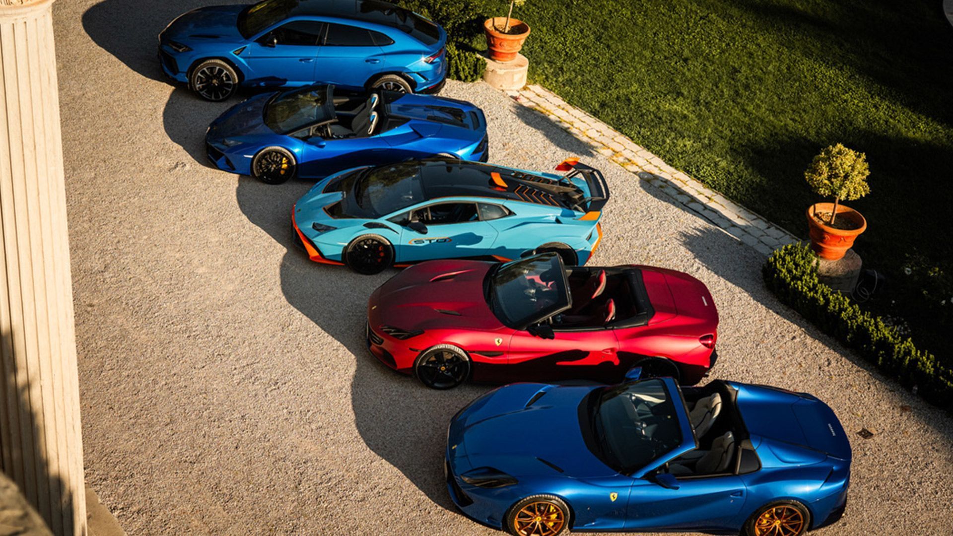 A row of sports cars are parked in a driveway.