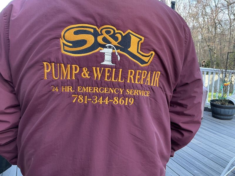 Person in maroon jacket with S&L Pump & Well Repair logo standing outdoors on a deck.