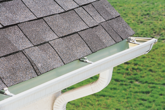 Roofers on a ladder repairing gutters on a gray house roof