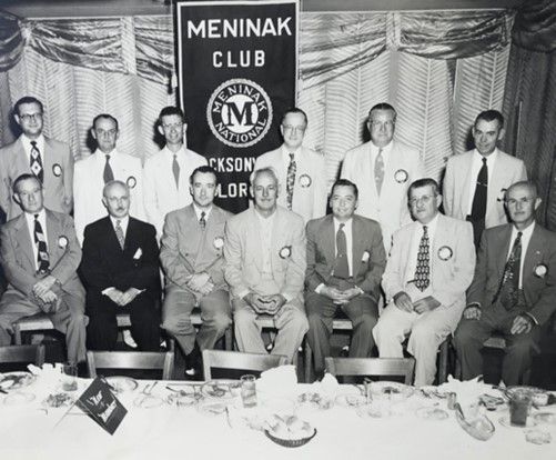 A woman in a blue jacket is standing in front of a group of people.