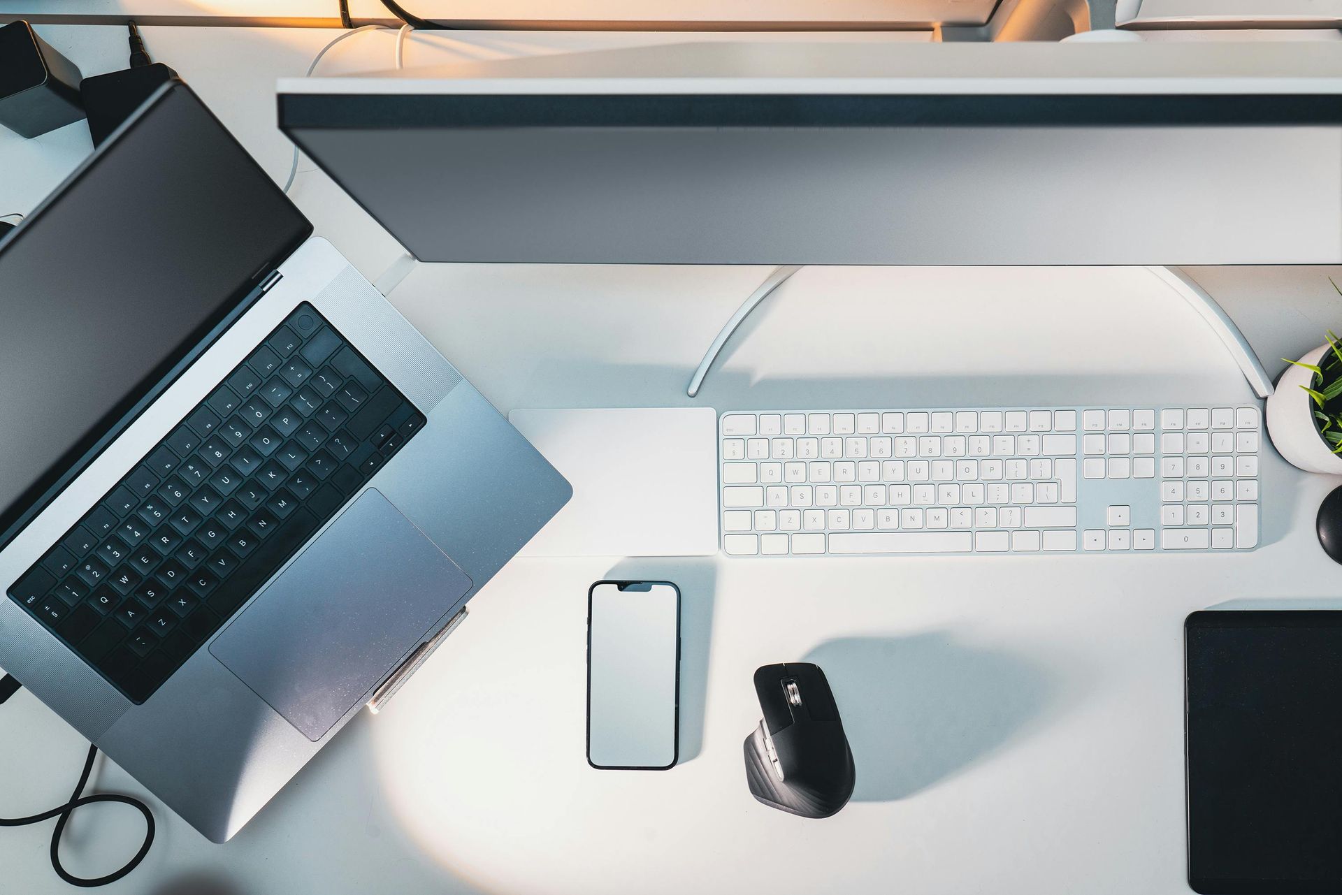 A desk with a laptop , computer , keyboard , mouse and cell phone.