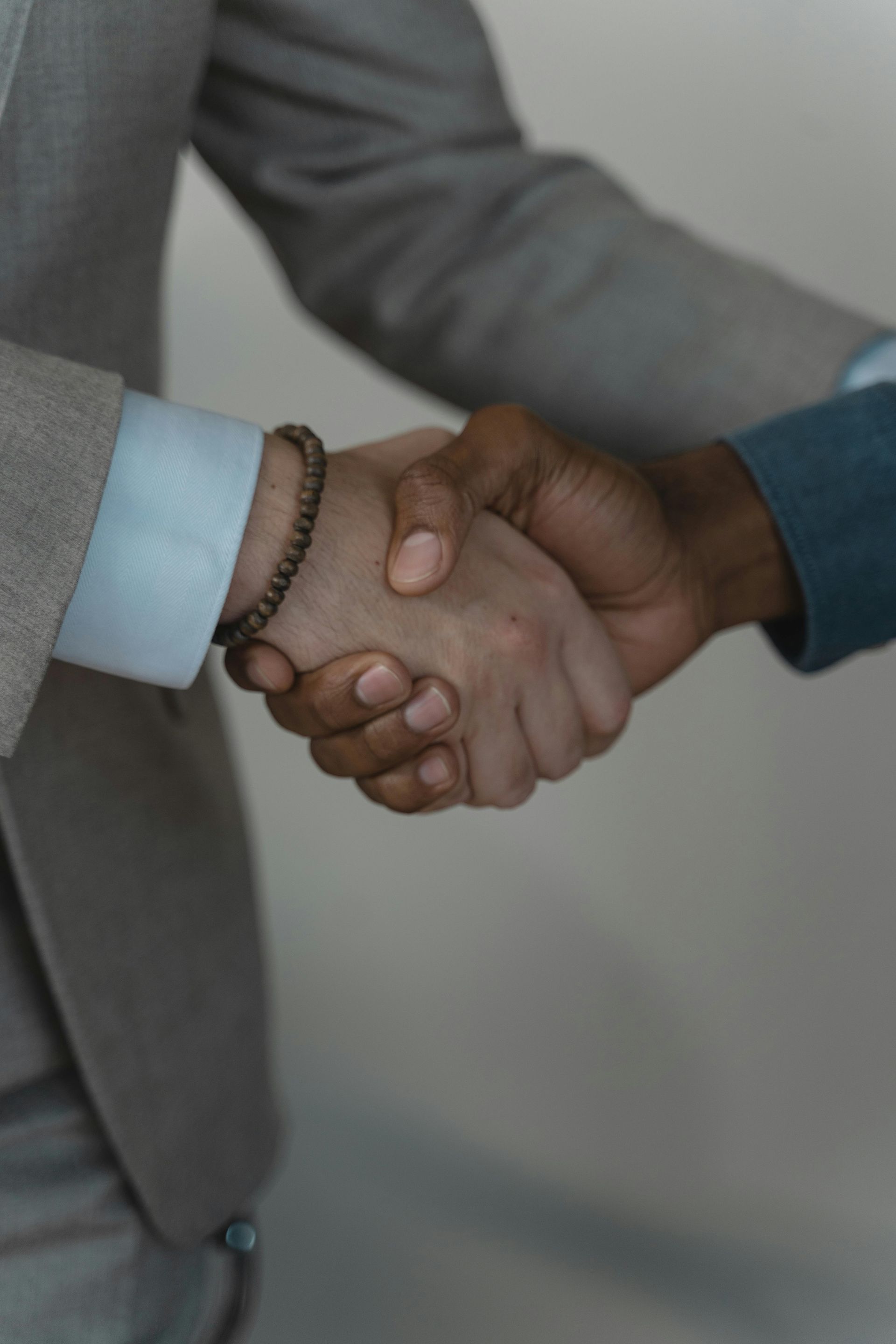 Two men are shaking hands in a close up of their hands.