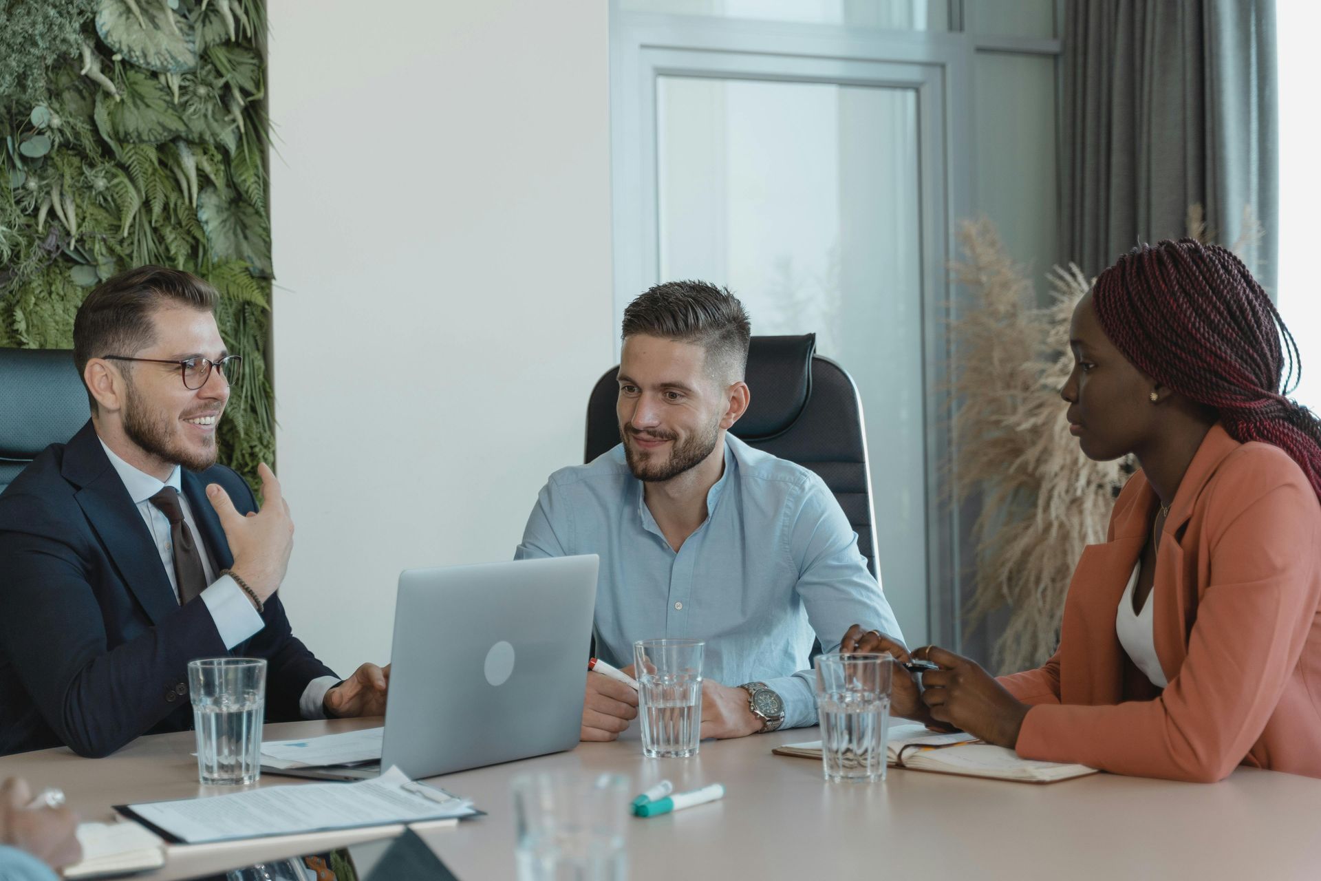 A group of people are sitting around a table with a laptop.
