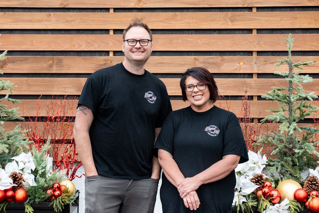 Two people wearing black shirts, standing in front of a holiday display.