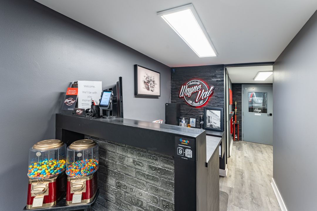 A tattoo parlor reception area with a front desk, gumball machines, and gray walls.