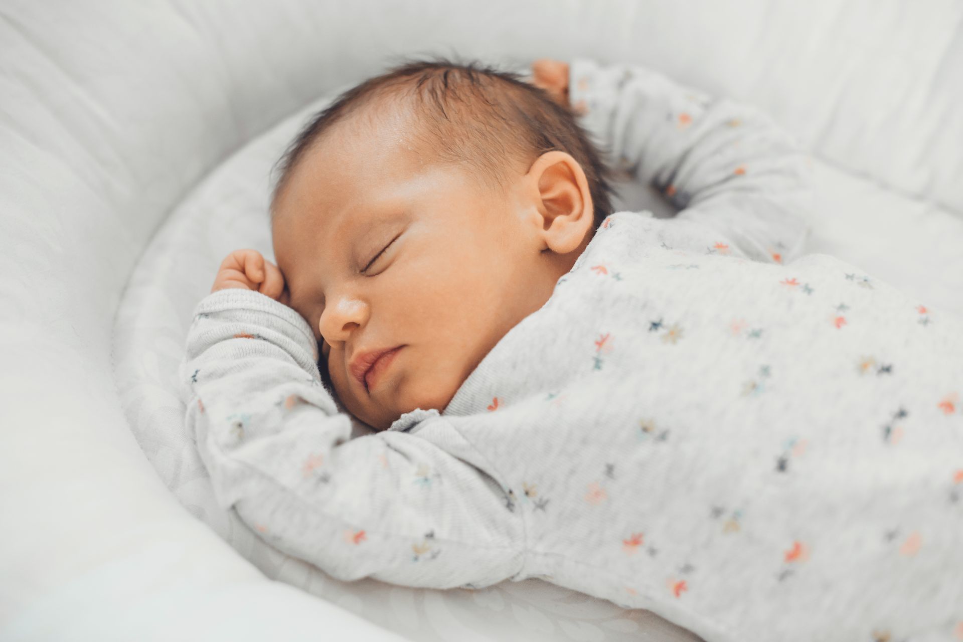 Smiling baby lying on white pillows and blanket in a bright bed Smiling baby lying on white pillows and blanket in a bright bed