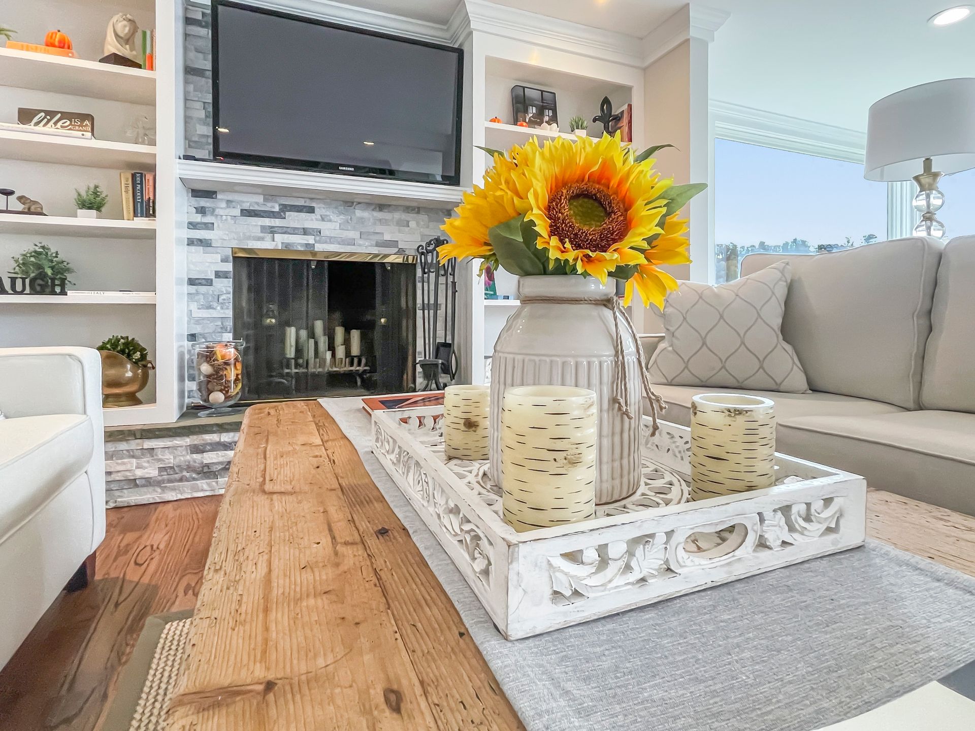 Two wicker armchairs with white cushions and striped pillows sit on a porch facing an ocean sunset.
