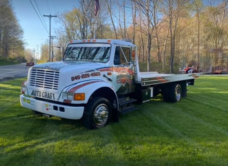A white tow truck is parked in a grassy field.