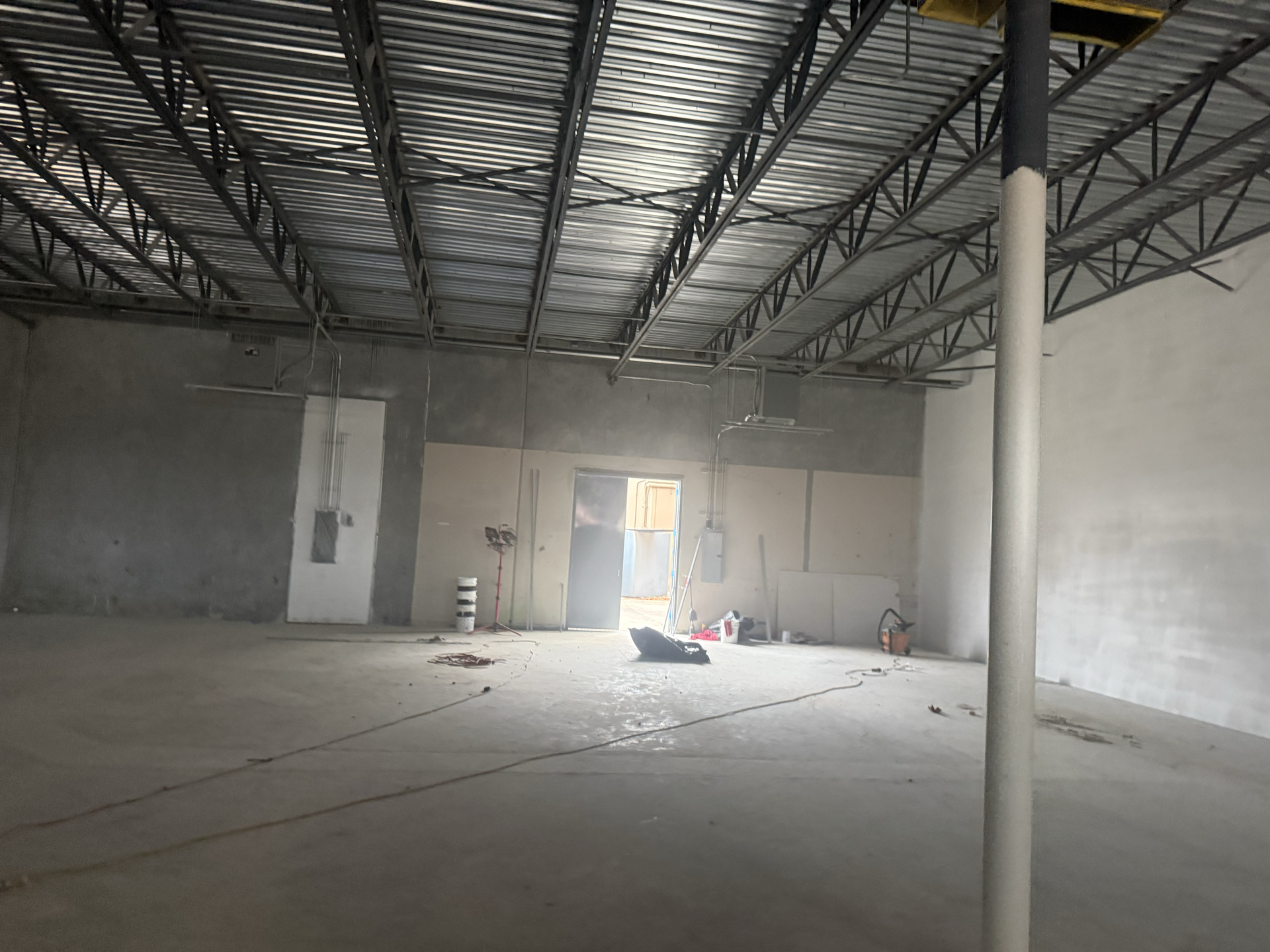 Interior of unfinished commercial space with metal ceiling and concrete floor.