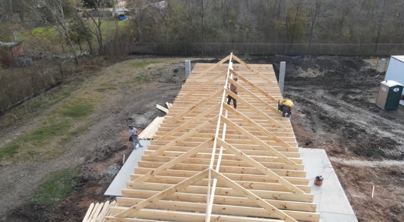 Construction workers building roof trusses on a new home. Wooden framework, outdoor setting.