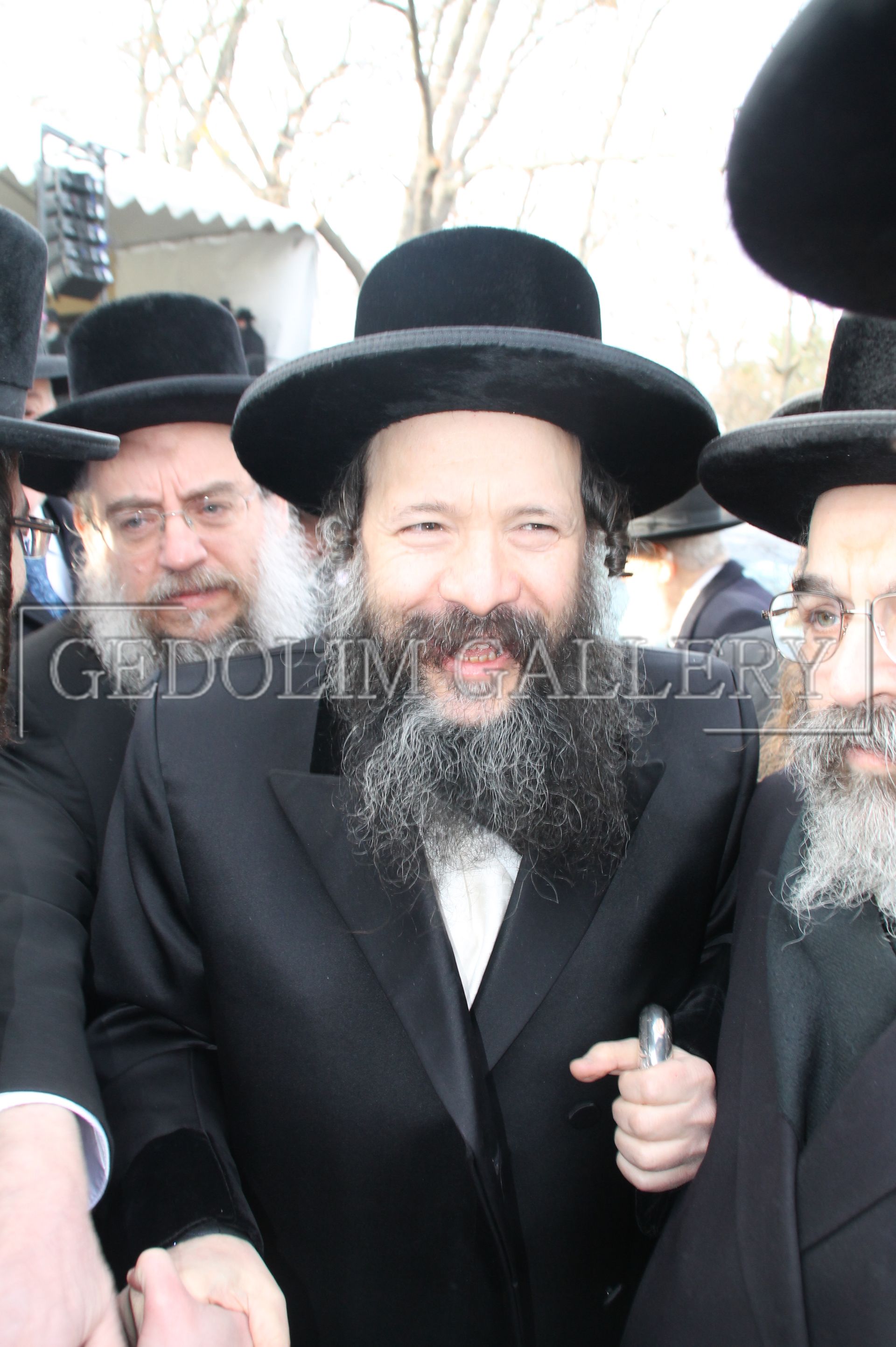 A man with a beard wearing a black hat and a white shirt