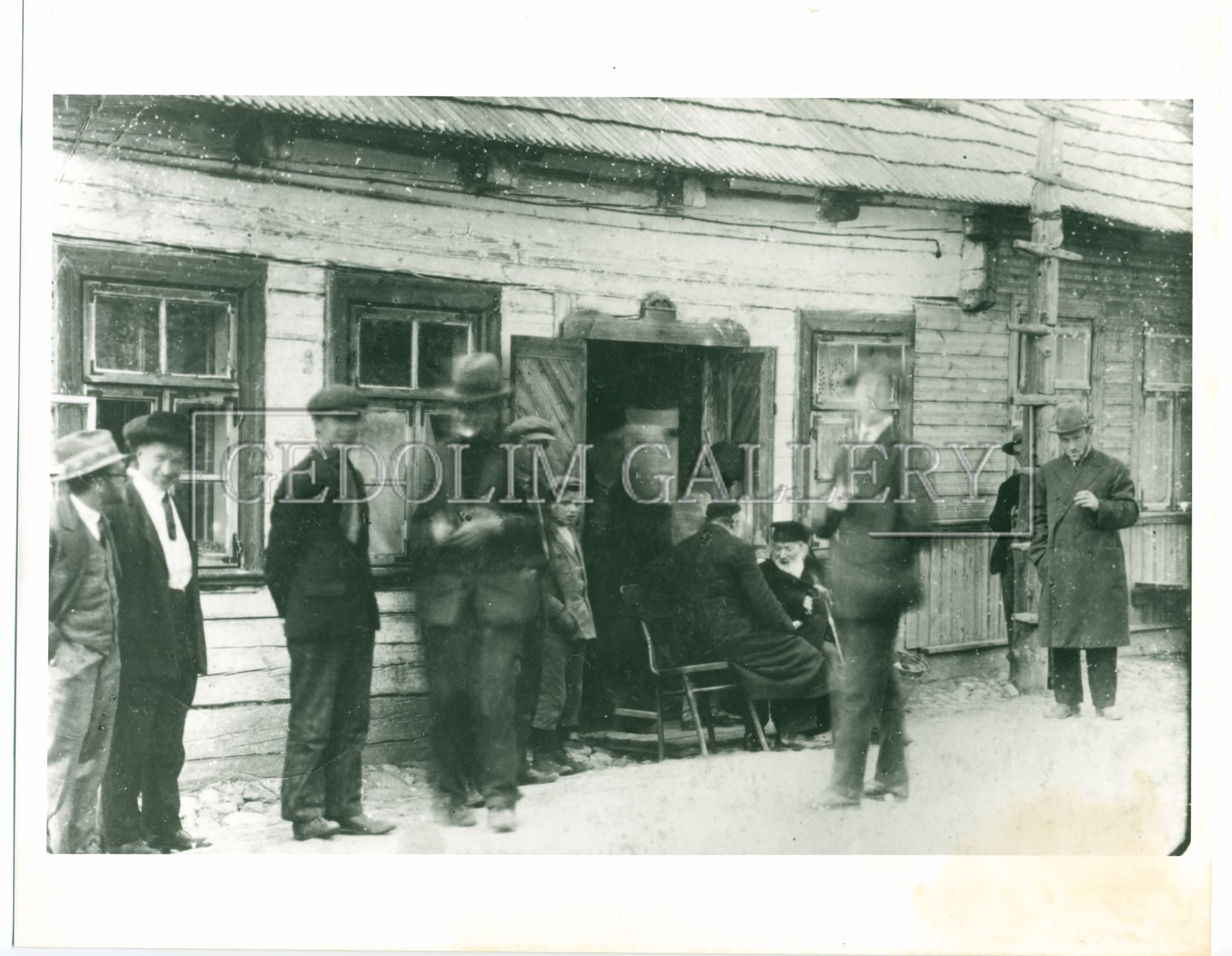 A black and white photo of a group of men standing outside of a wooden building