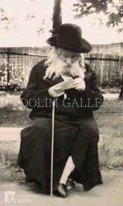 A man with a beard is kneeling down with a cane.