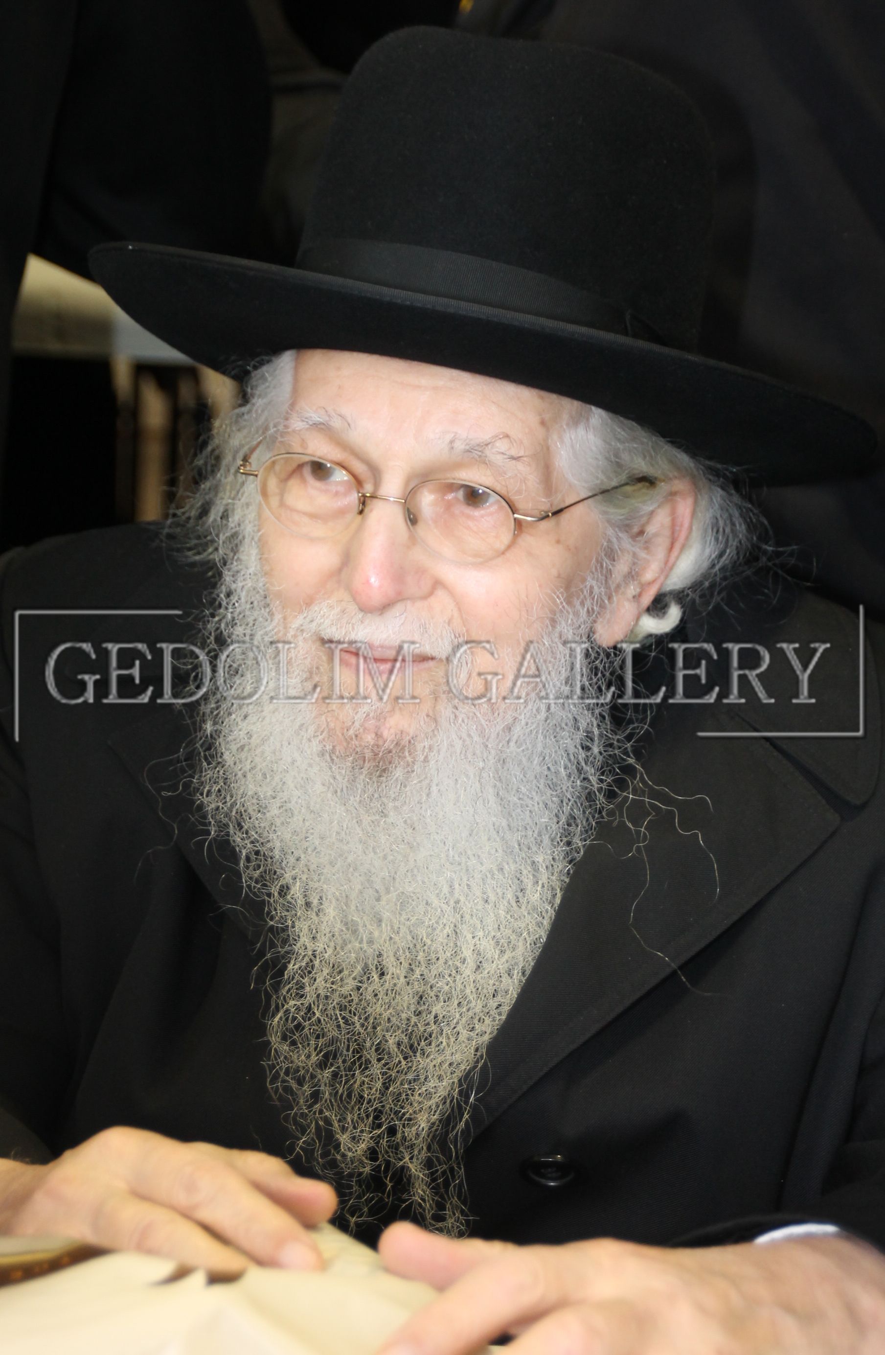 A man with a beard and glasses is wearing a black hat