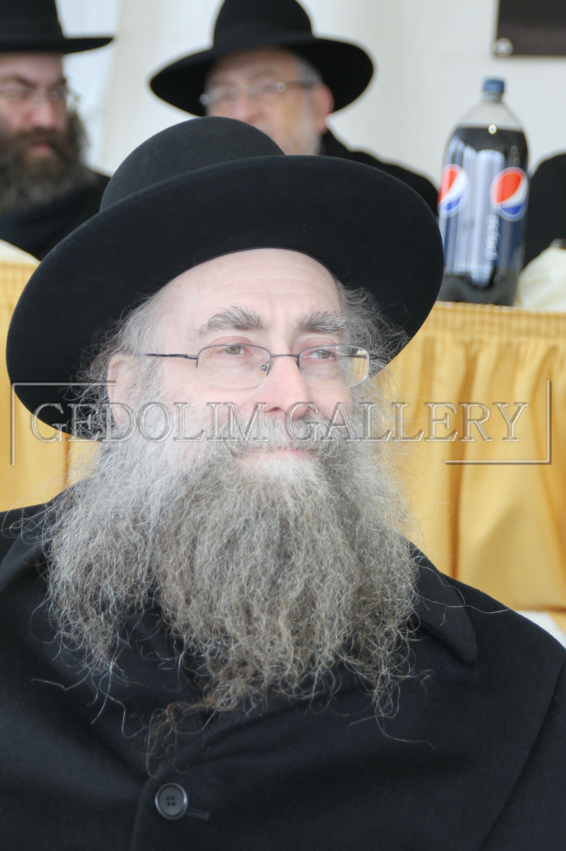 A man with a beard wears a black hat and glasses