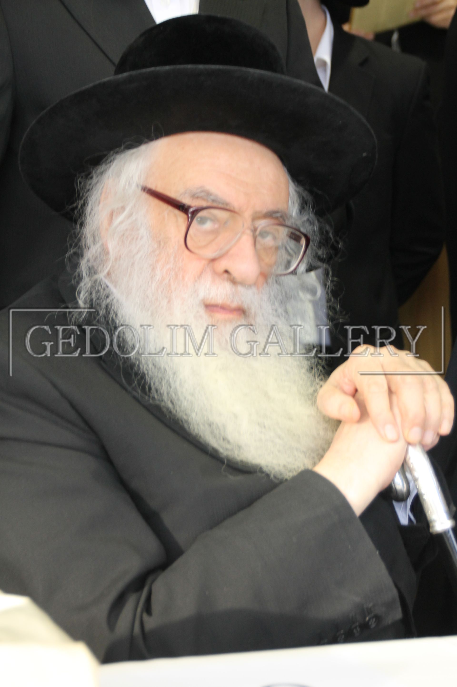 A man with a beard and glasses is wearing a black hat