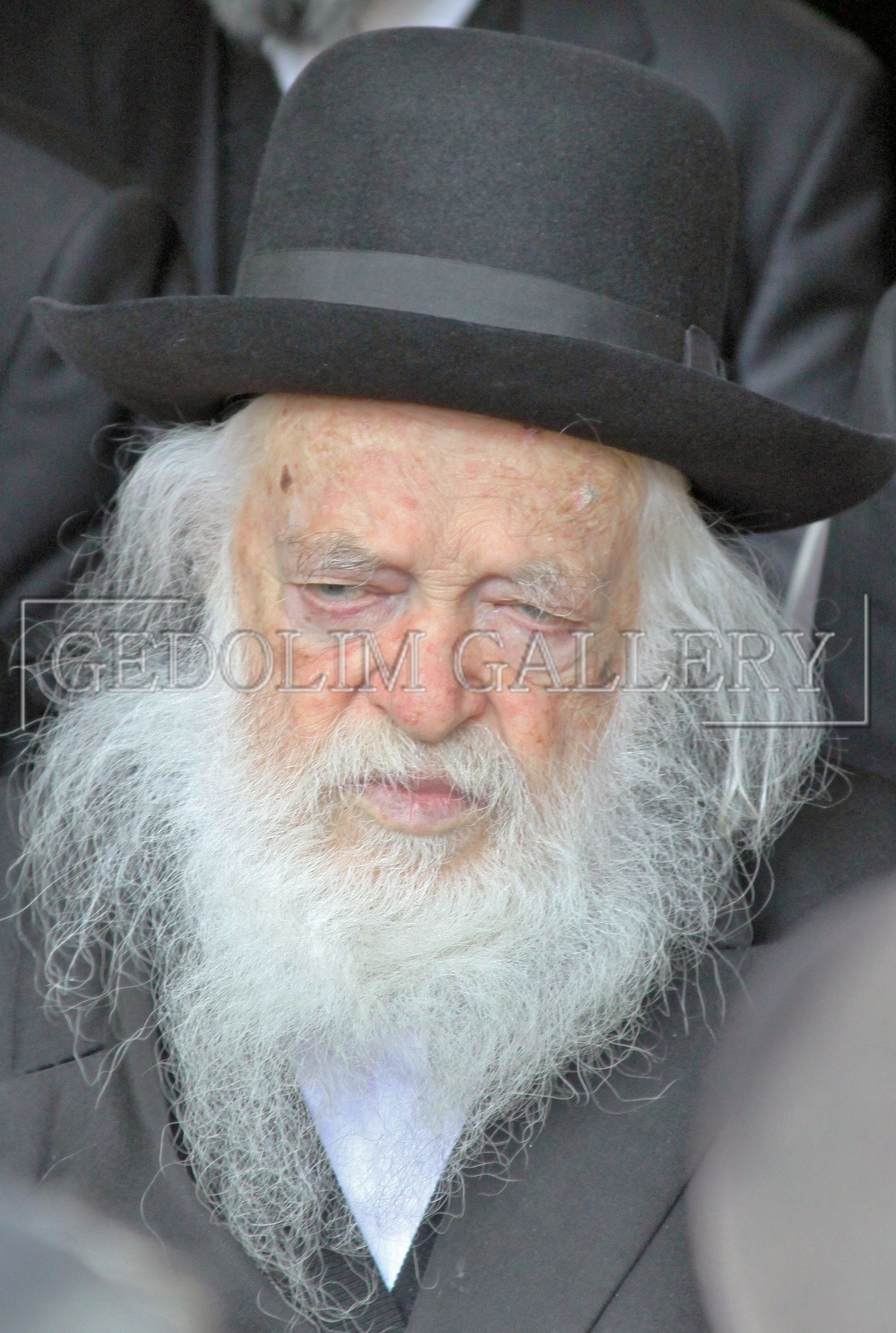A man with a beard is wearing a hat and a suit.