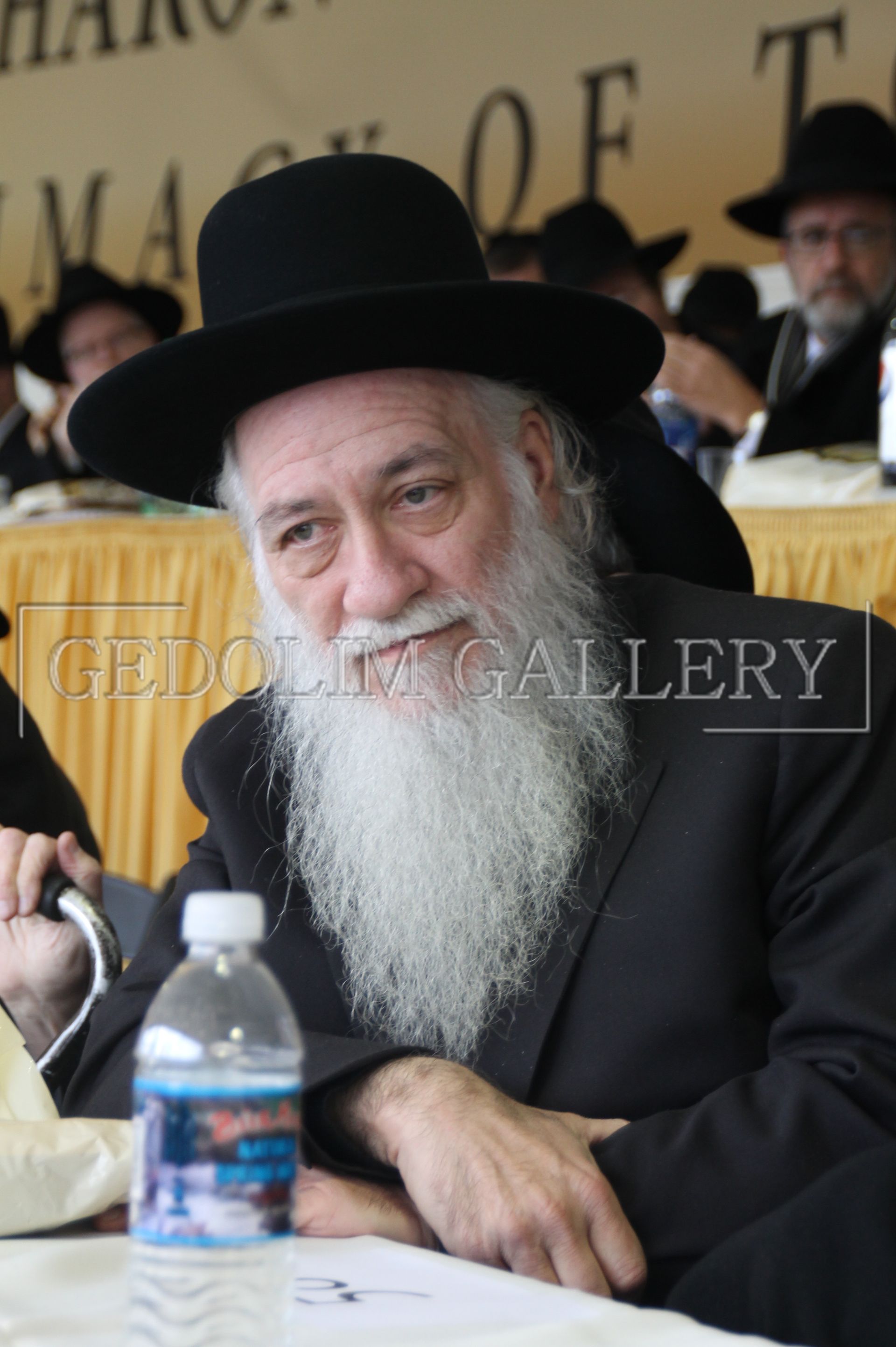 A man with a beard is sitting at a table with a bottle of water