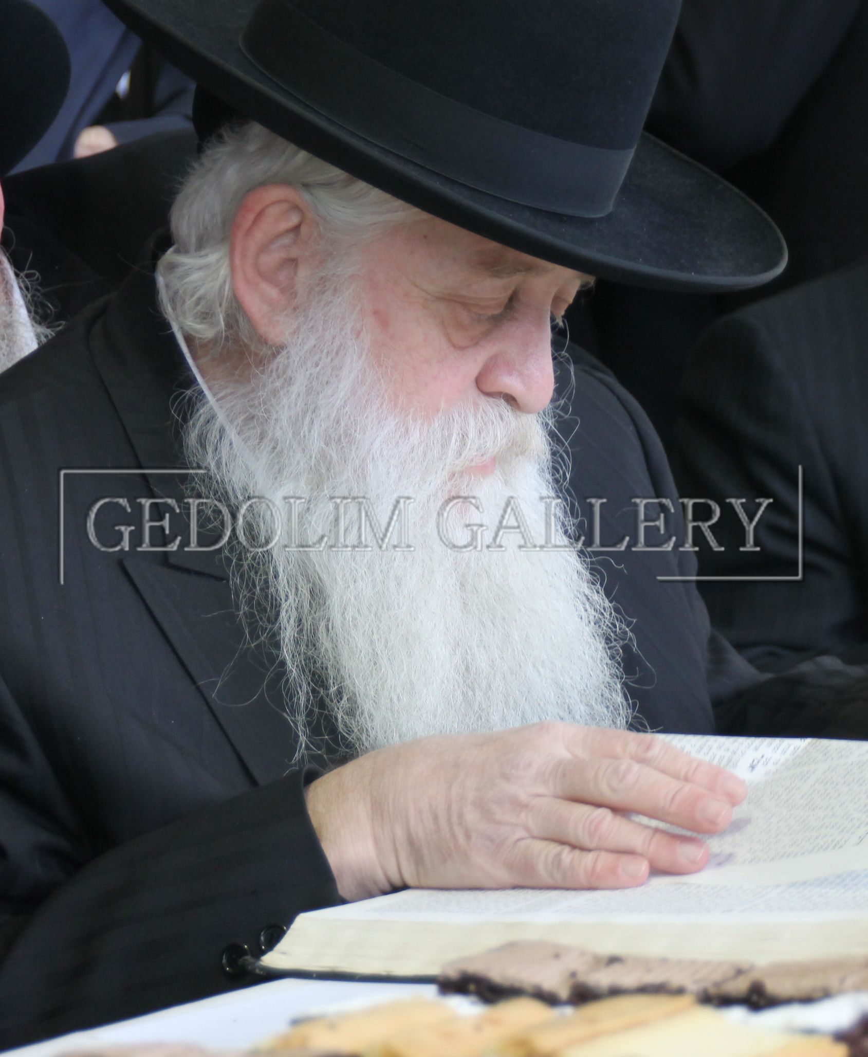 A man with a beard wearing a top hat is reading a book