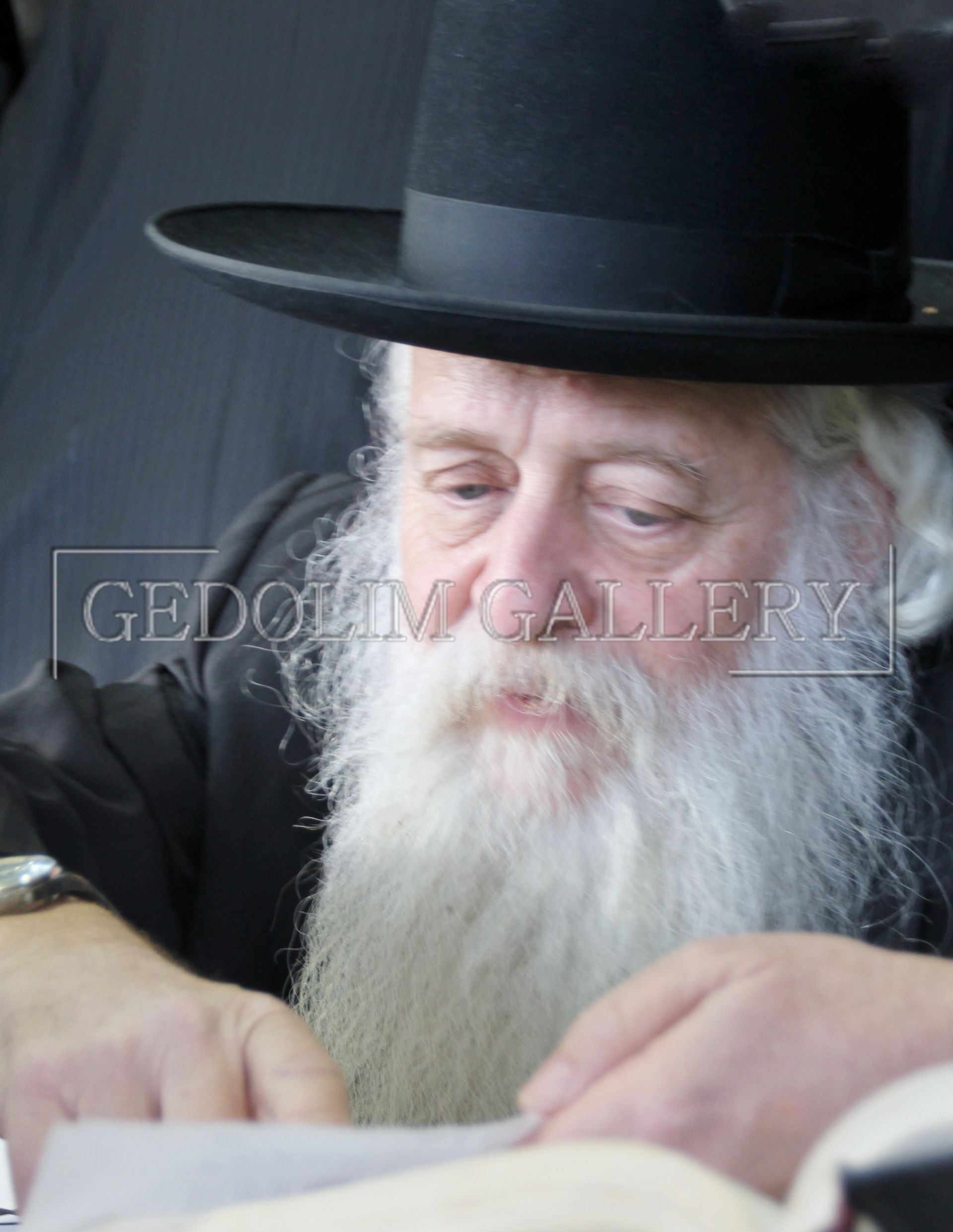 A man with a beard wearing a black hat is looking at something