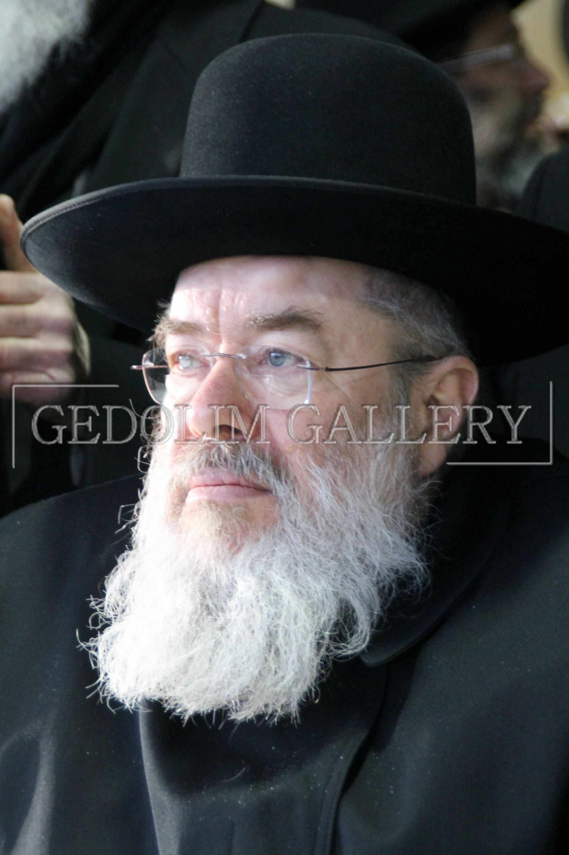 A man with a beard and glasses is wearing a black hat