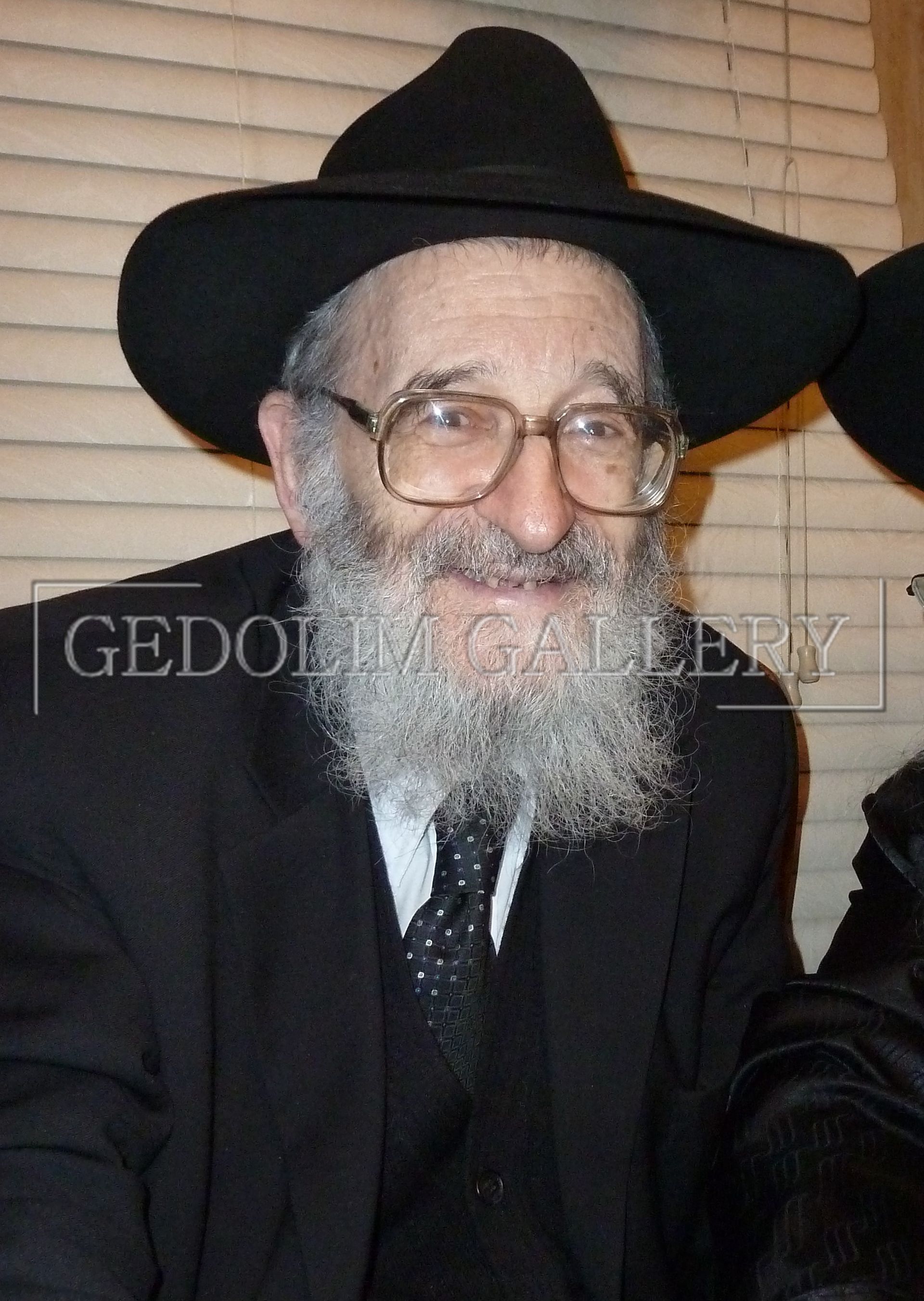 A man with a beard wearing a black hat and glasses