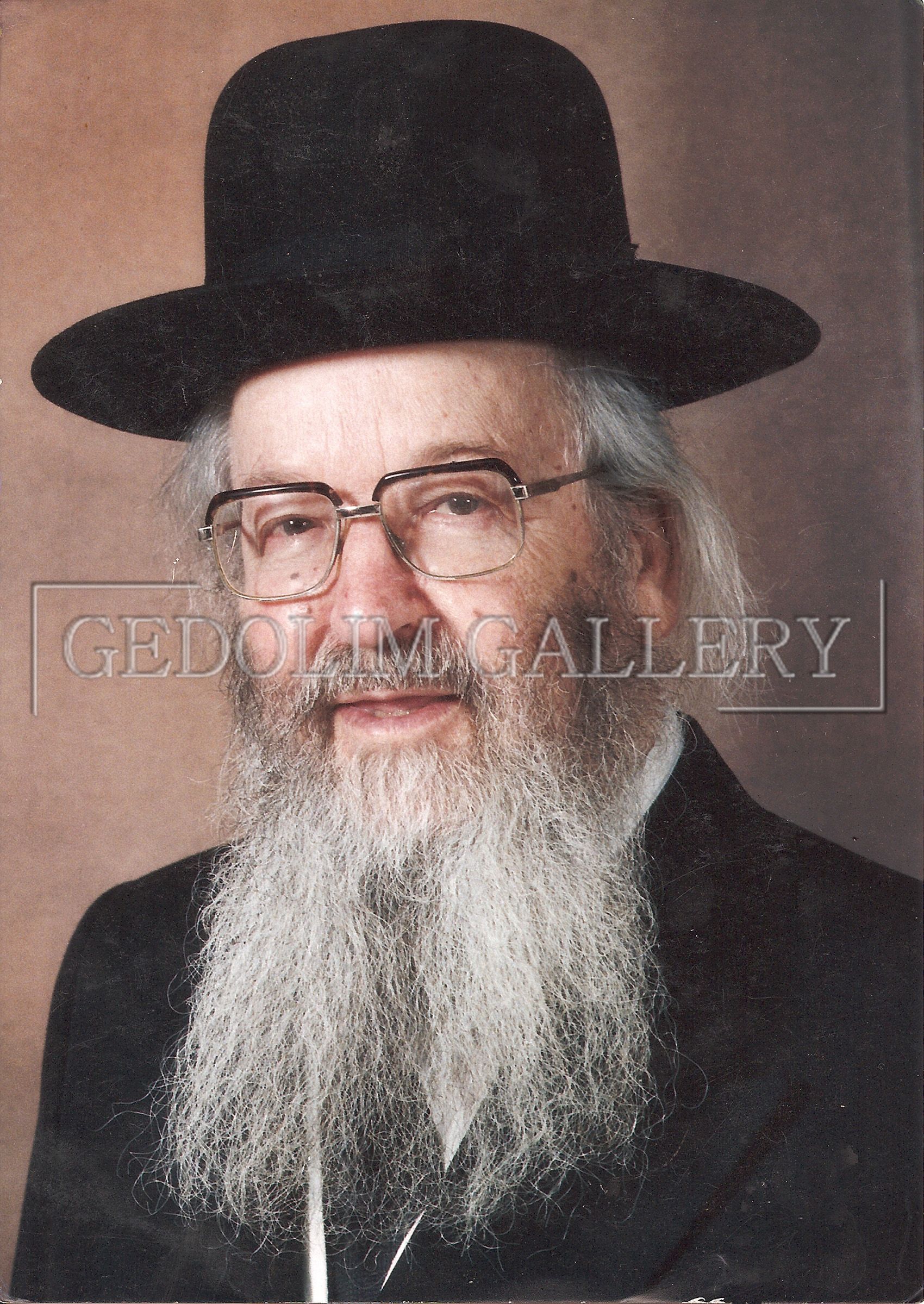 A man with a beard and glasses is wearing a black hat