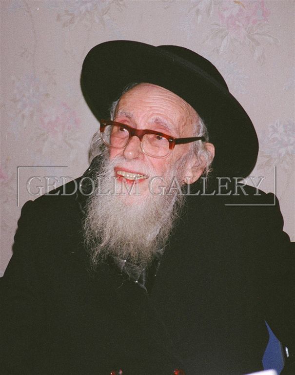 A man with a beard and glasses is wearing a hat and smiling