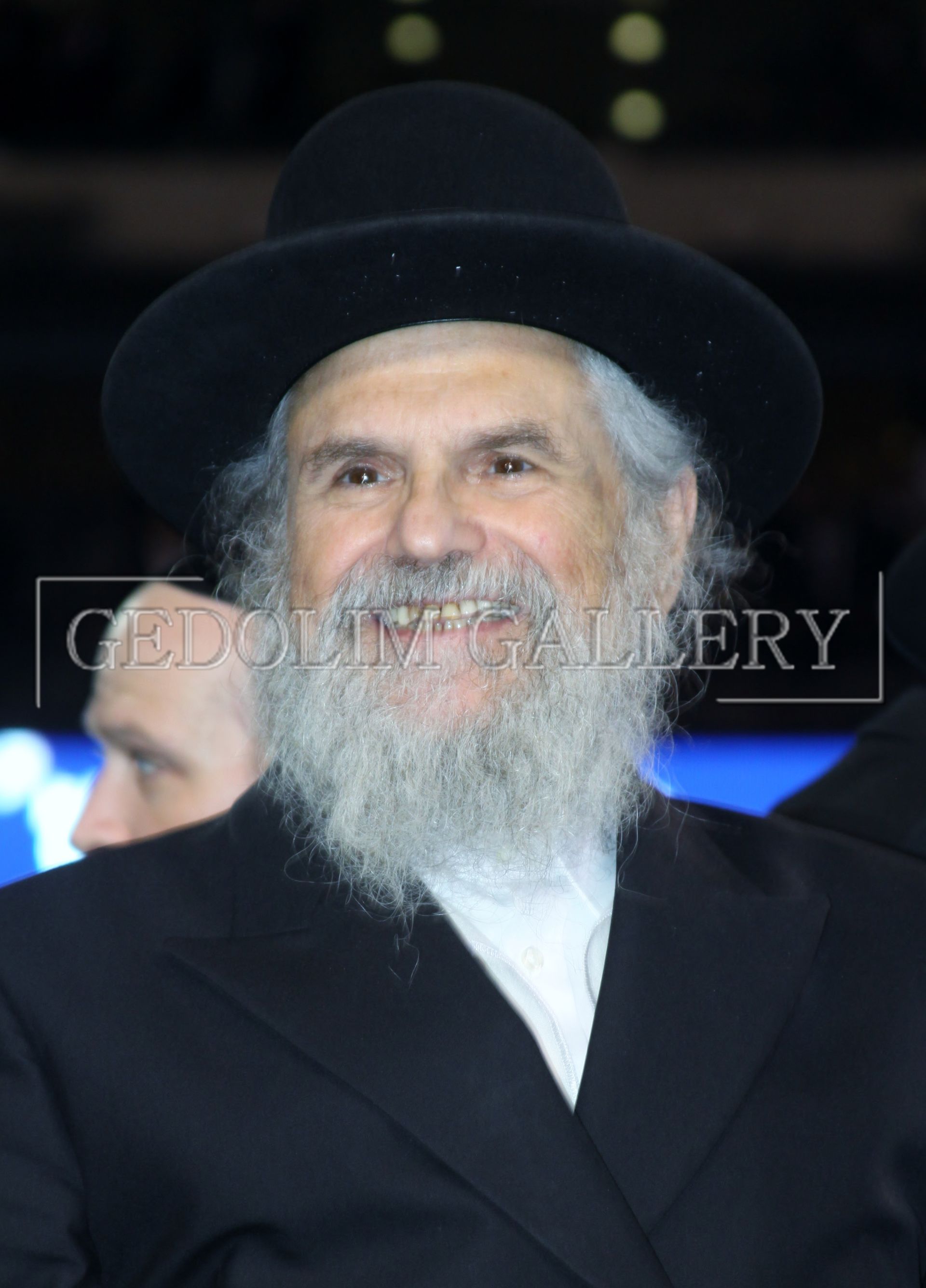 A man with a beard wearing a black hat and a white shirt