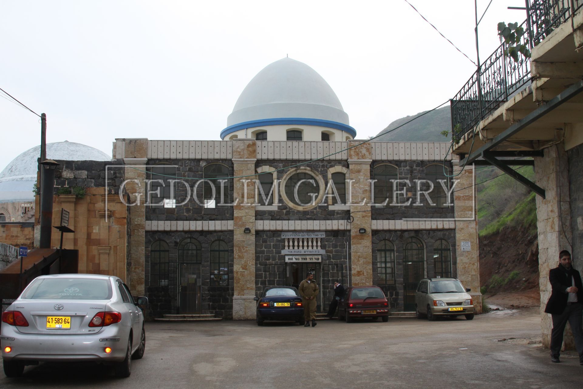 Cars are parked in front of a building that says gedolin gallery