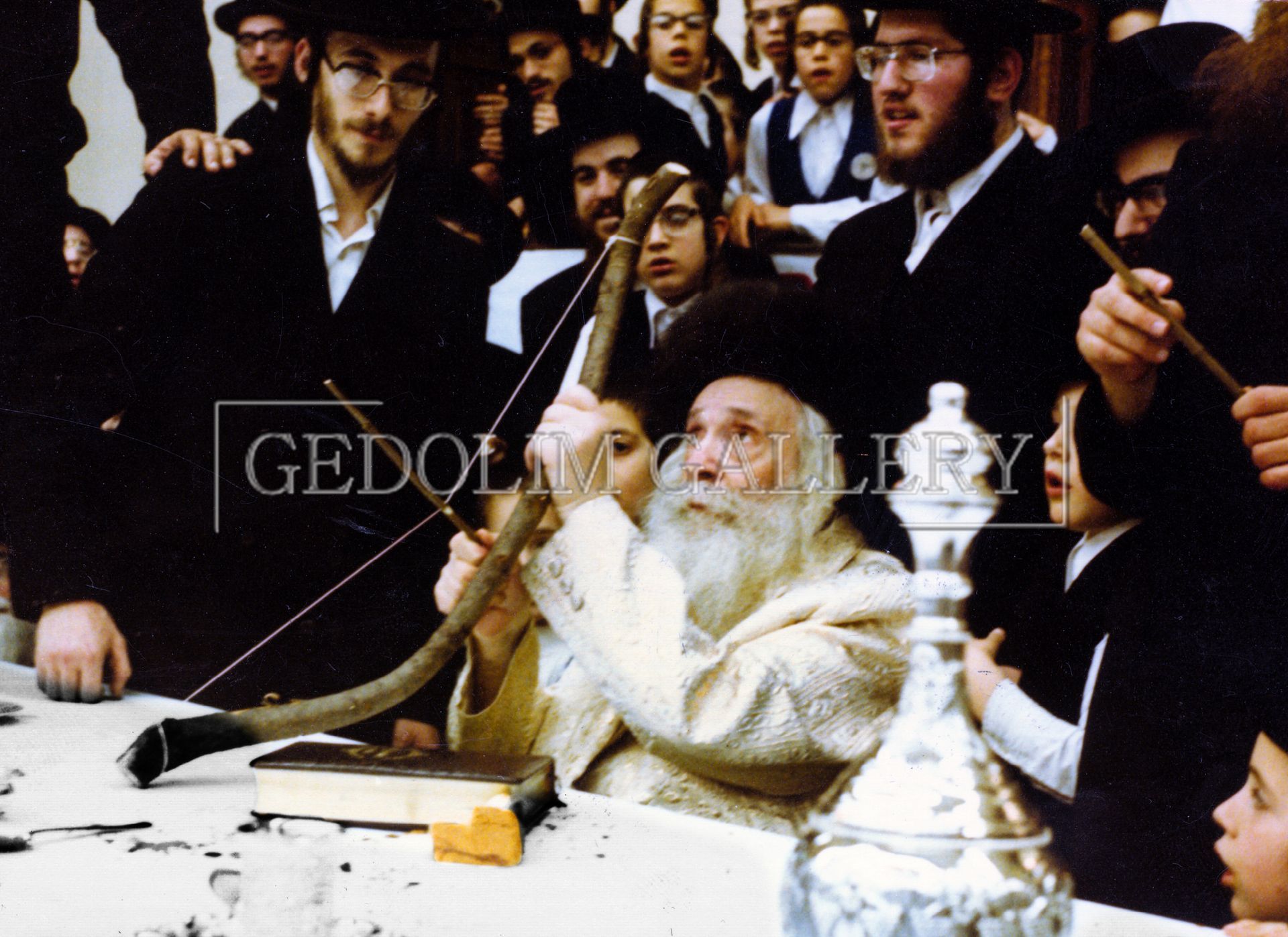A group of men are gathered around a man holding a shofar