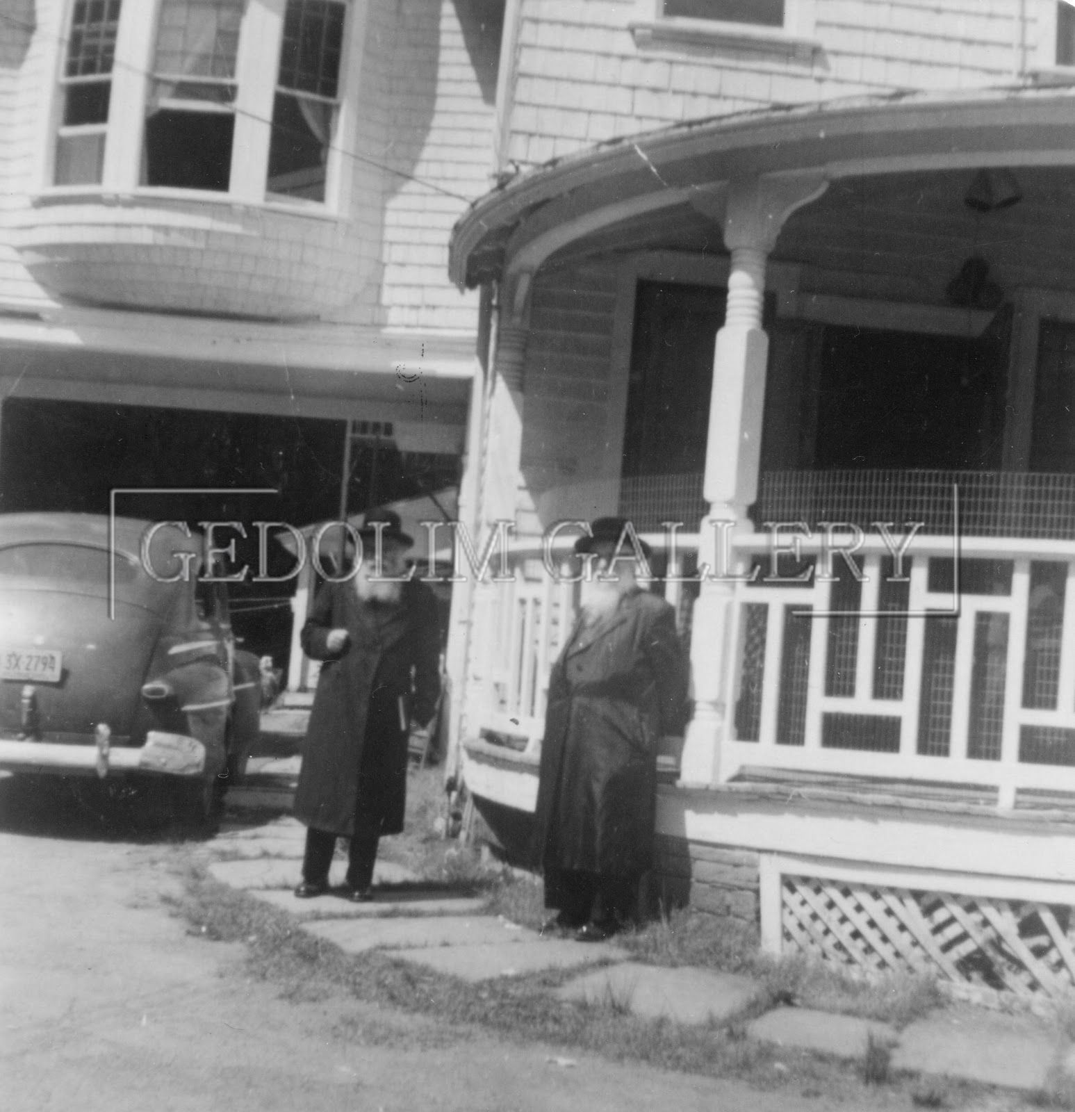 A black and white photo of two people standing in front of a house